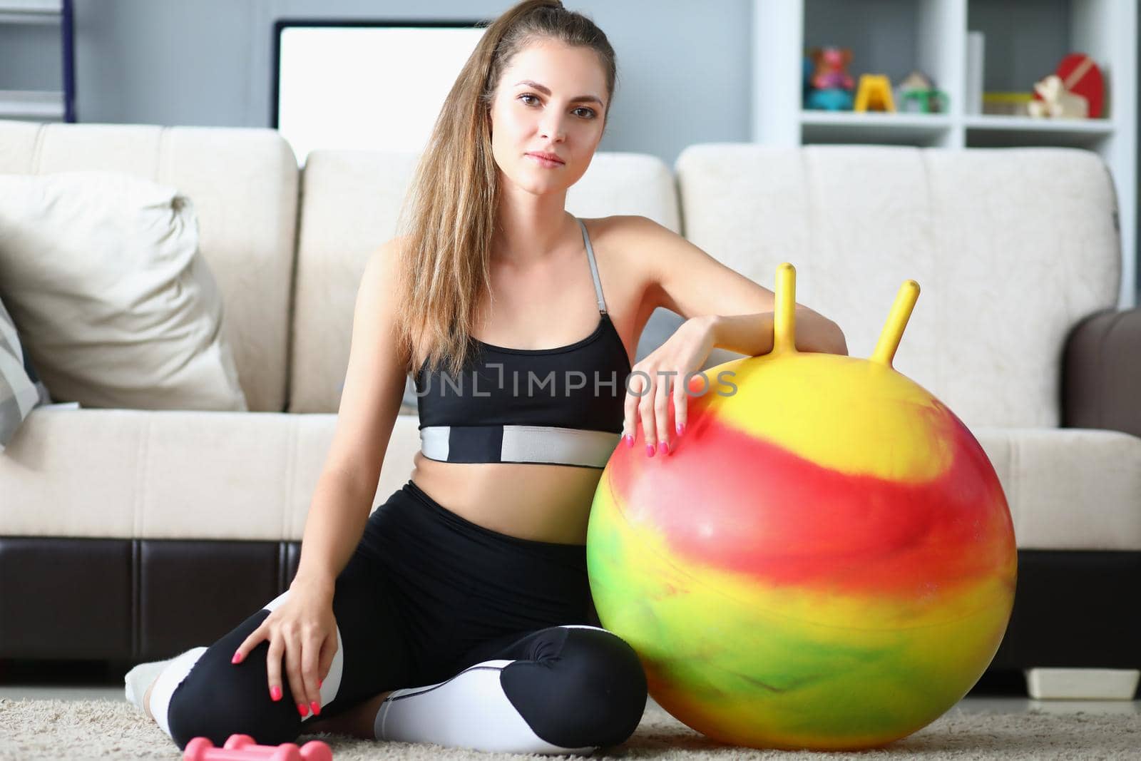 Attractive young woman pose with dumbbells and ball on floor by kuprevich