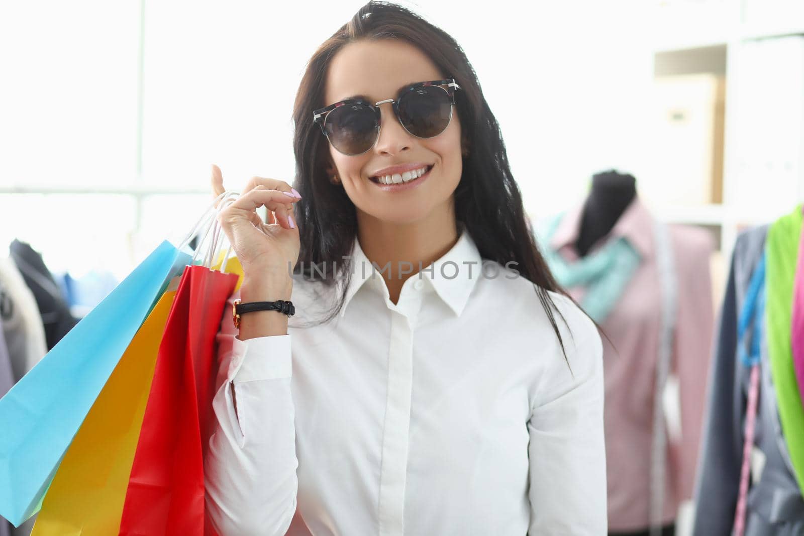 Portrait of young woman shopaholic smiling and carry packages with clothes. Girl carry many packs with bought stuff. Big sale, shopping, discount concept