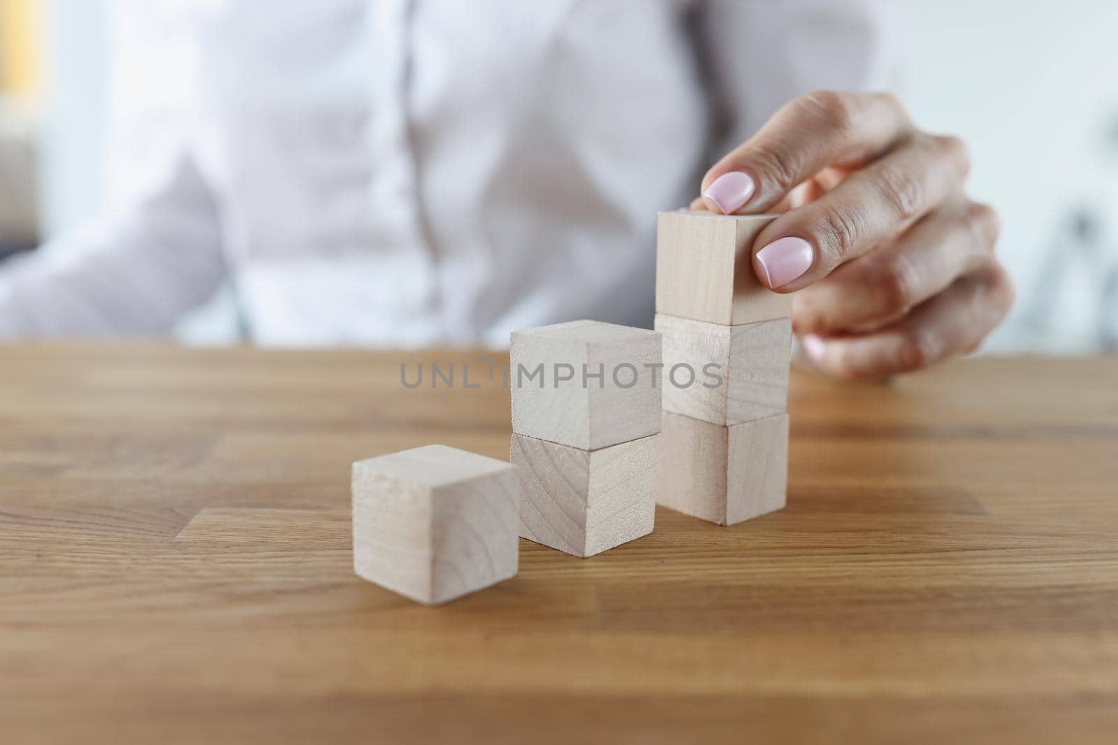 Close-up of female putting wooden brick on top of stack, building tower. Visualizing future plans. Planning, management, strategy, business goal concept