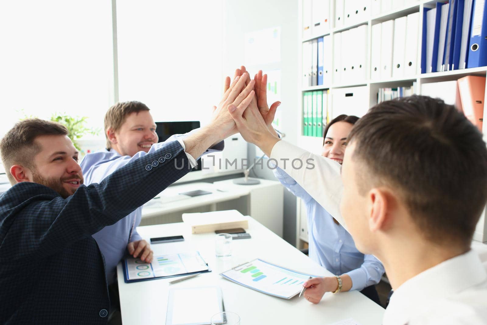 Witty colleagues performing high five gesture in order to celebrate important profitable project by kuprevich