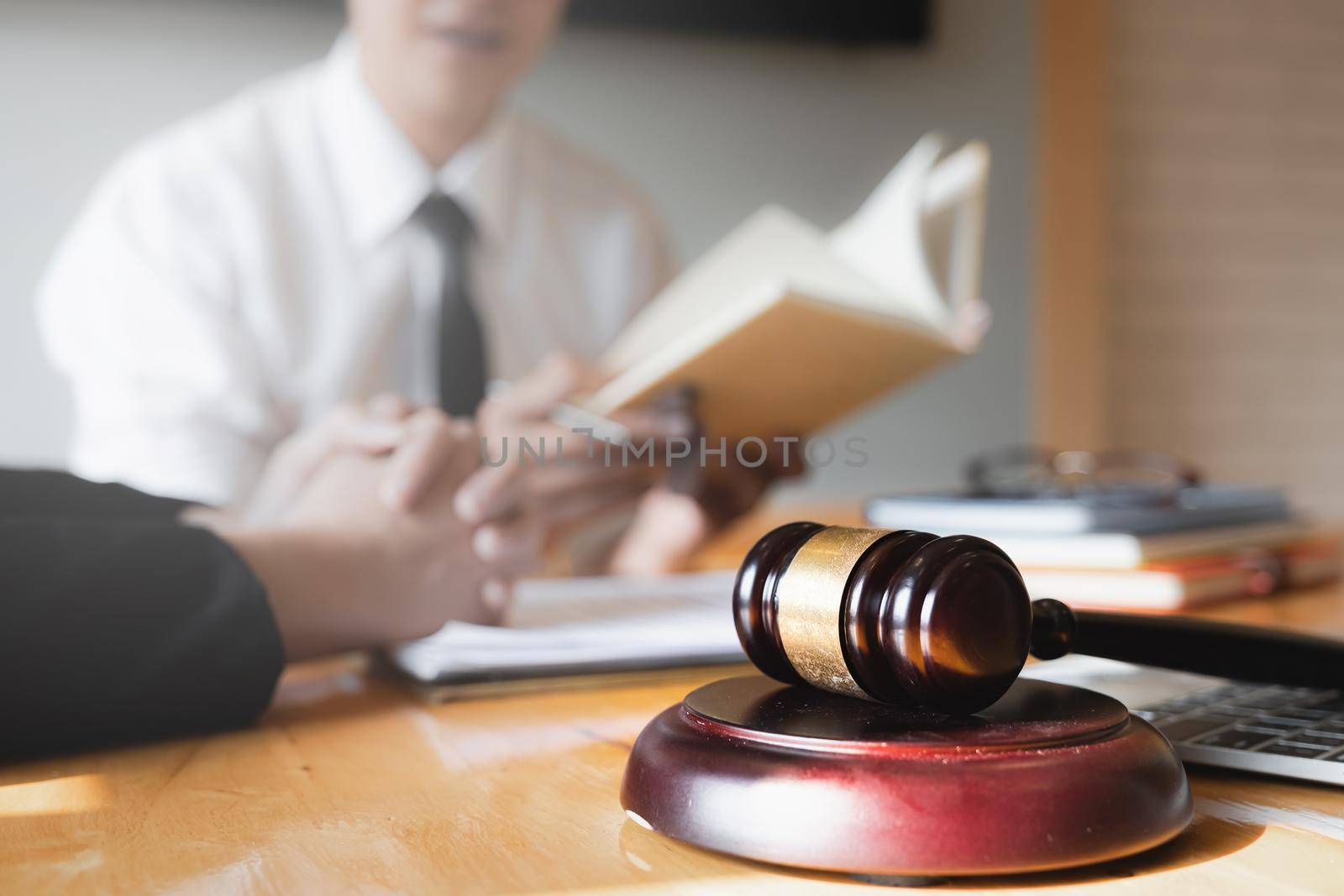 Business woman and lawyers discussing by lawyer book with brass scale on wooden desk in office. Law, legal services, advice, Justice concept.