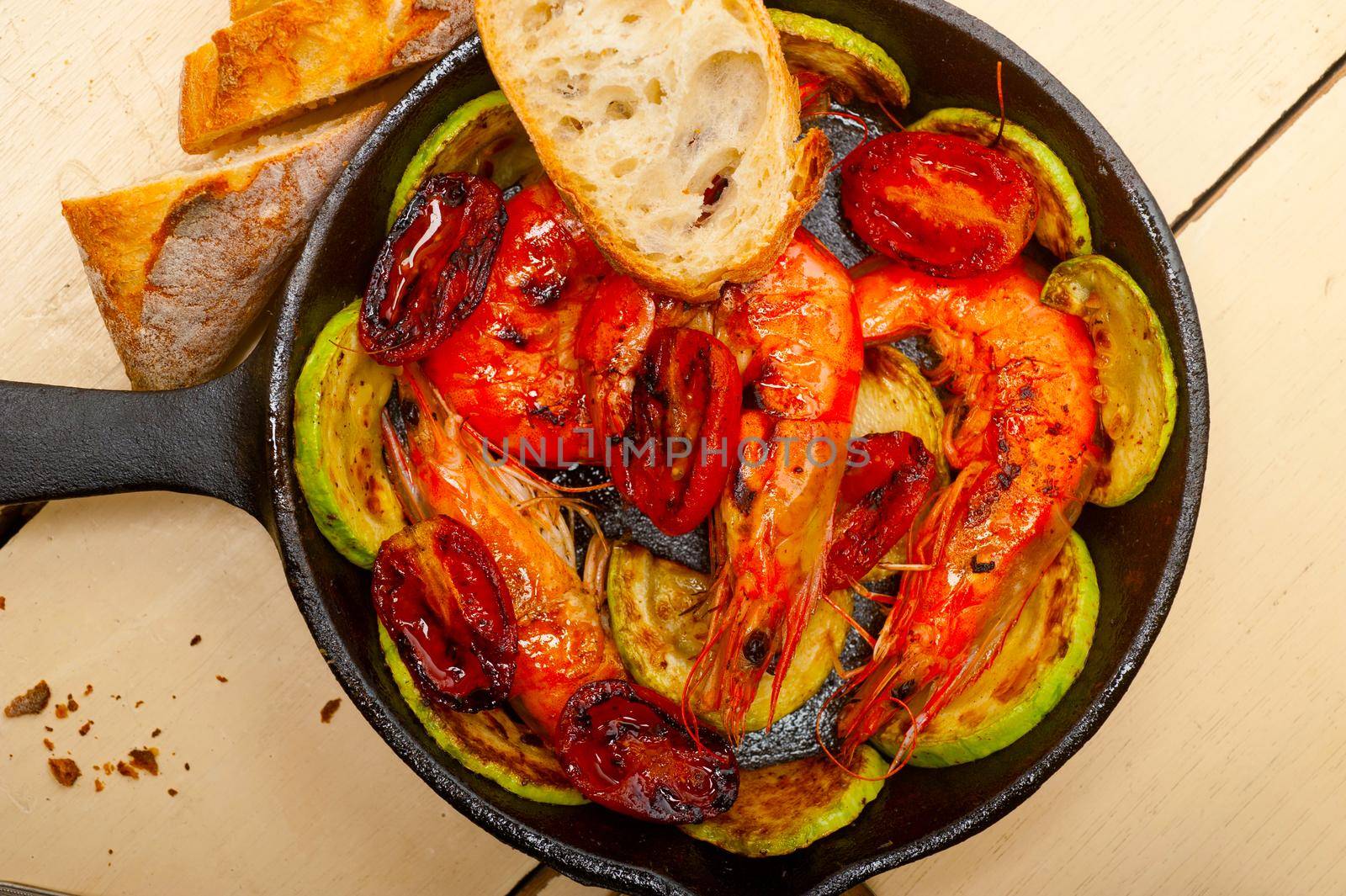 roasted shrimps on cast iron skillet  with zucchini and tomatoes