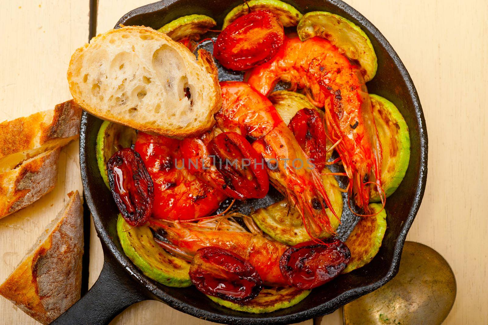 roasted shrimps on cast iron skillet  with zucchini and tomatoes