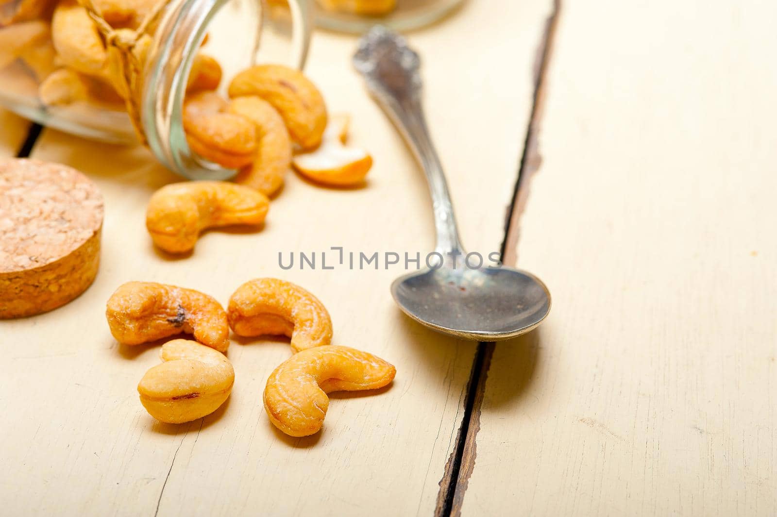 cashew nuts on a glass jar over white rustic wood table 