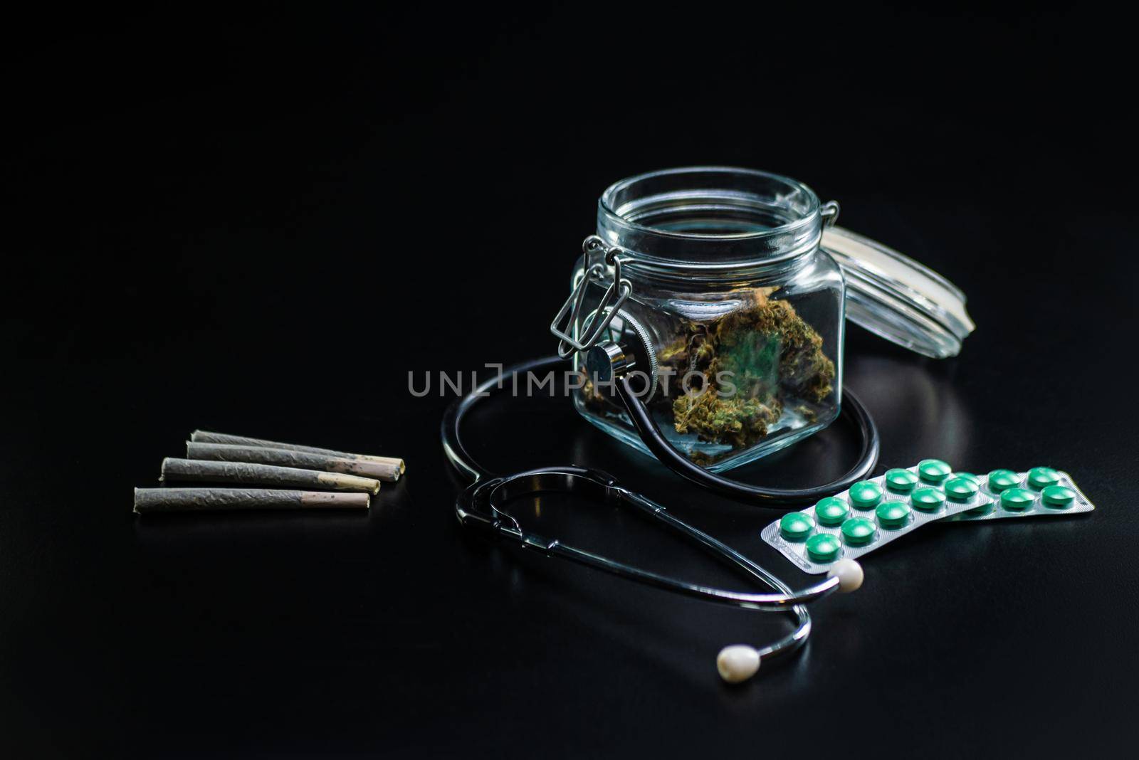 the Dry medical cannabis in a jar with a stethoscope on a black background