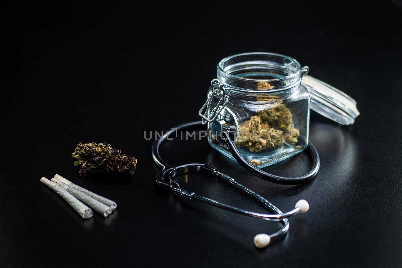 the Dry medical cannabis in a jar with a stethoscope on a black background