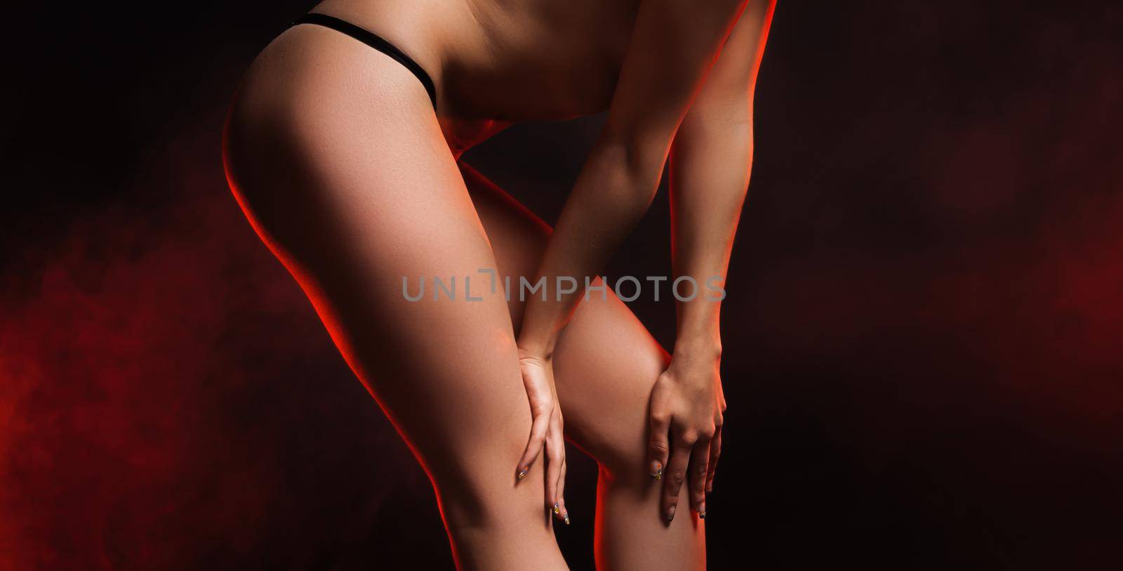 Young semi-nude woman in lace black panties posing in the studio on a dark background