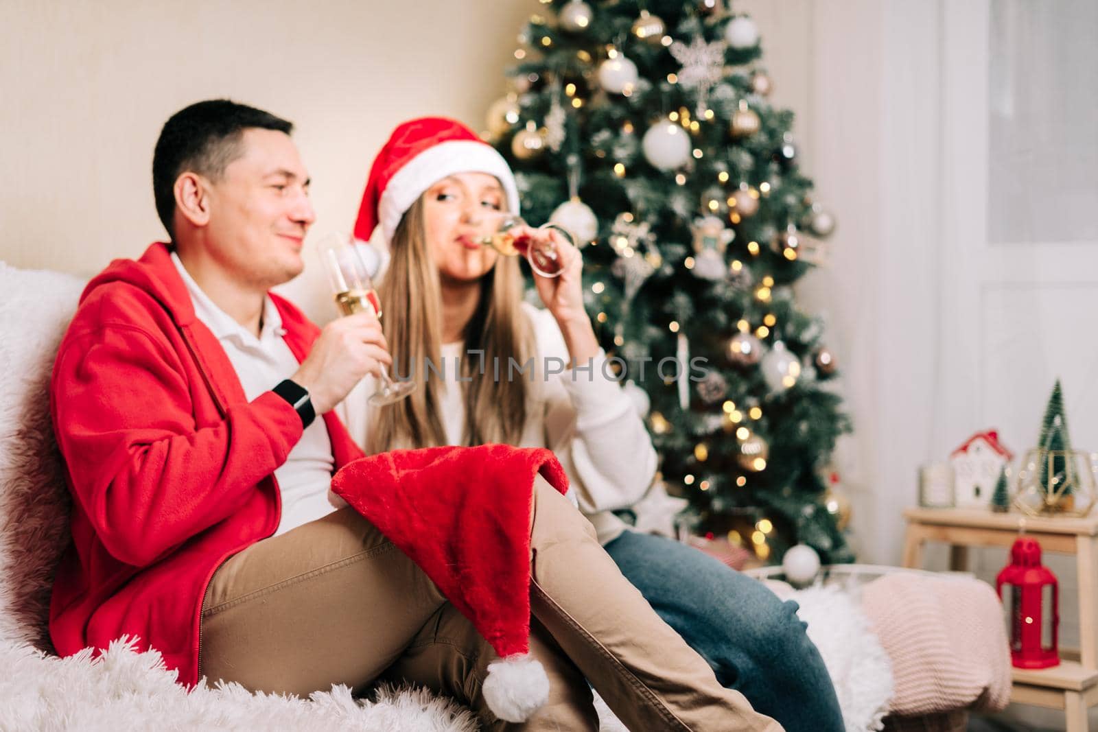Family couple with funny face, man and woman with champagne celebrate New year after Christmas holidays. Home decor with Christmas tree.