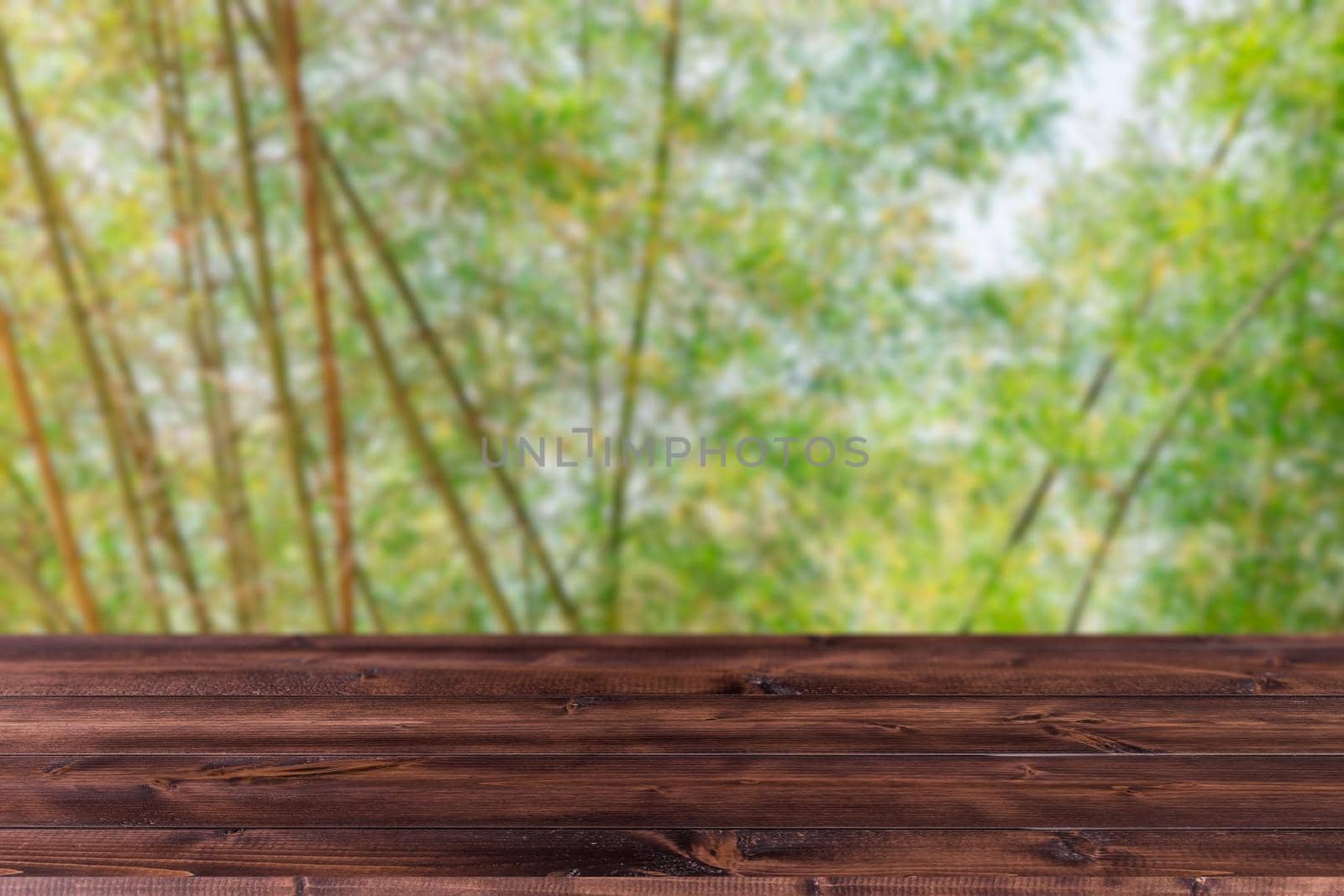 Blur green tree bamboo grove forest with wooden space forground for products montage advertising  background.