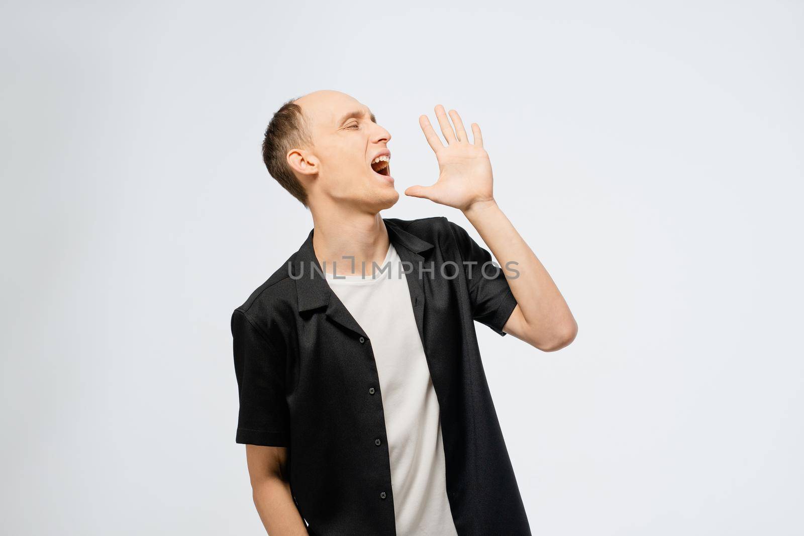 Portrait of a young half bald man wearing black shirt with white t-shirt underneath. Excited young adult happy man showing satisfaction with hands over white background in studio.