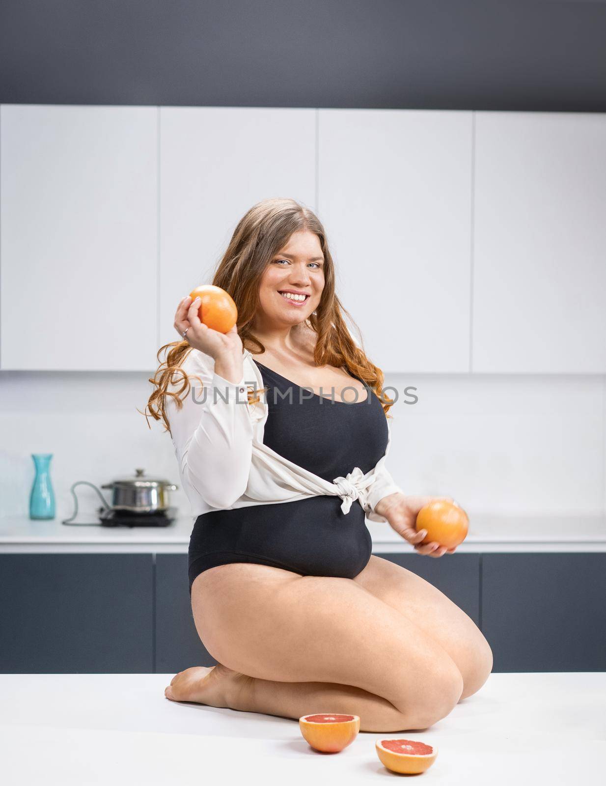 Girl sitting on the kitchen table. Young fat woman trying diet. Diet young fat woman standing on kitchen. Close up chubby female lowering BMI weight. Trying to loose weight fast healthy food.