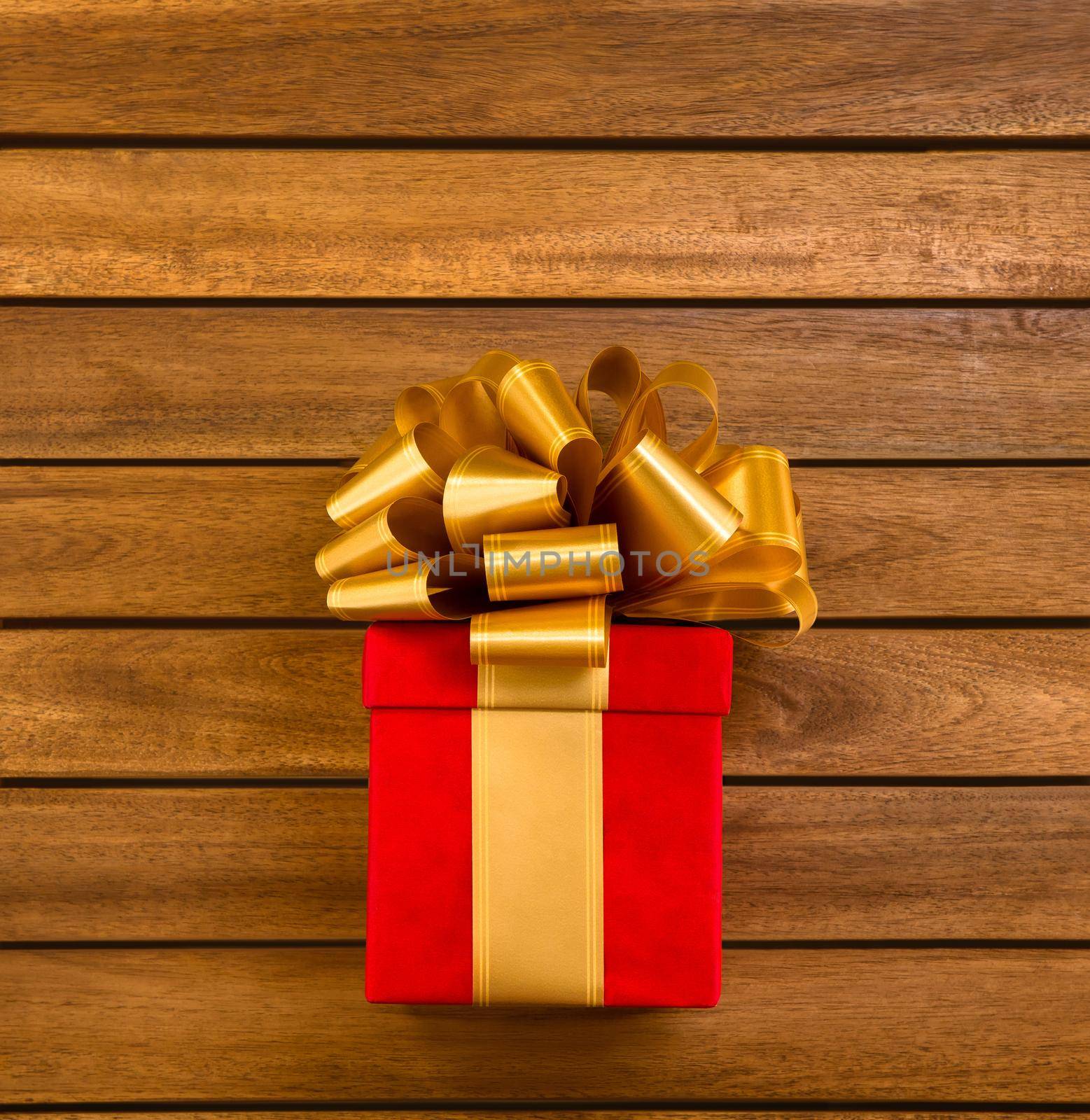 Red Square Gift Box with Gold Ribbon and Big Loopy Bow on it. Copy Space. Wooden Background. High quality photo