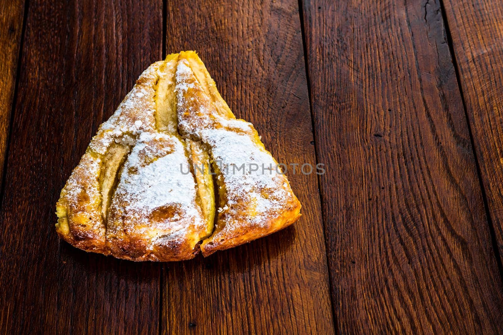 Sliced apple pie with cinnamon on rustic wooden table