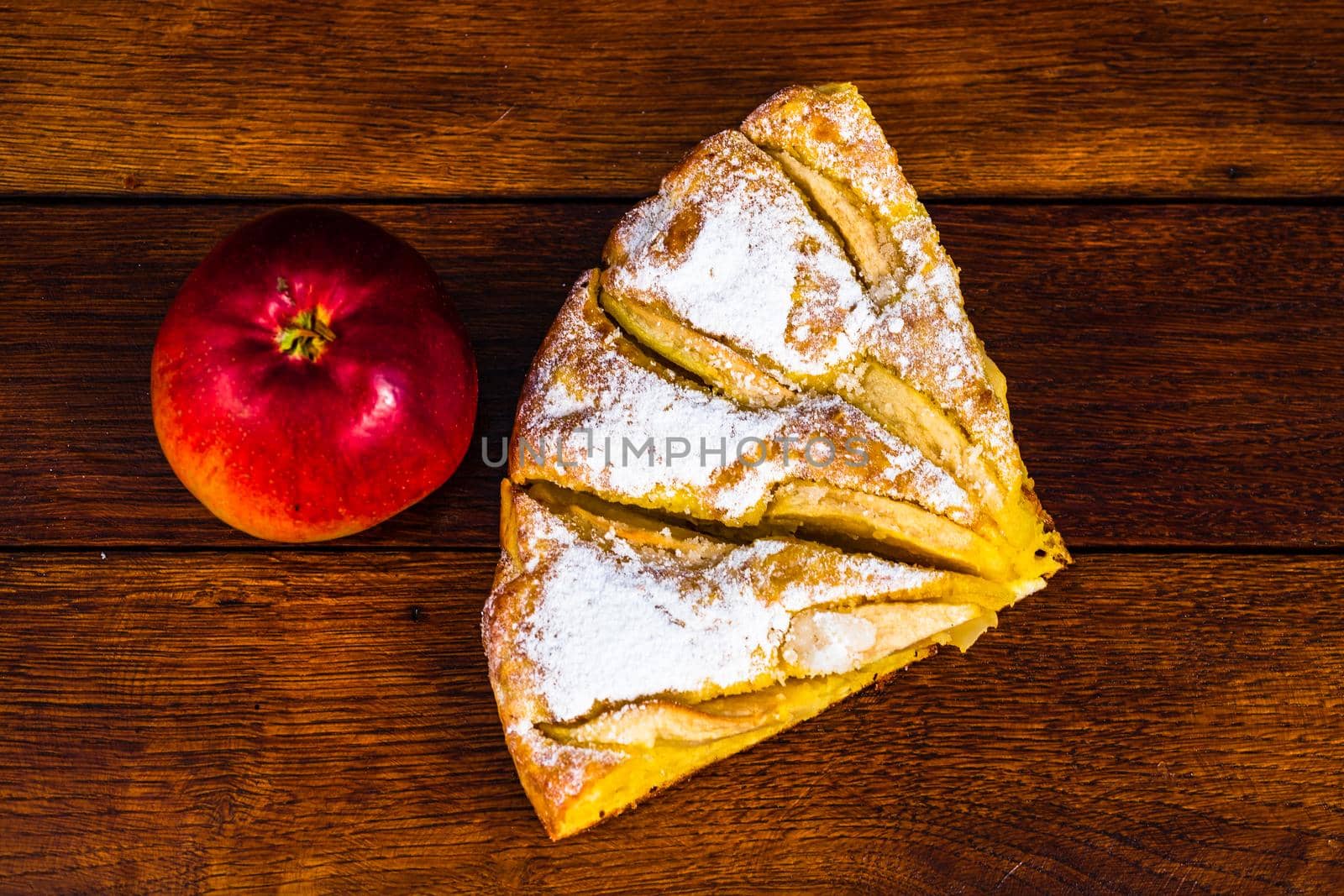 Sliced apple pie with cinnamon on rustic wooden table