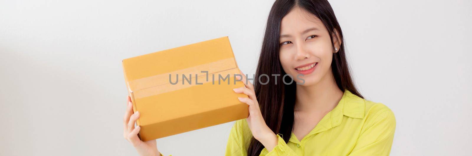 Young asian woman smiling and holding cardboard box with surprise at home, happy female carrying parcel box with excited, present and gift, packaging for deliver, online shopping store and service concept. by nnudoo