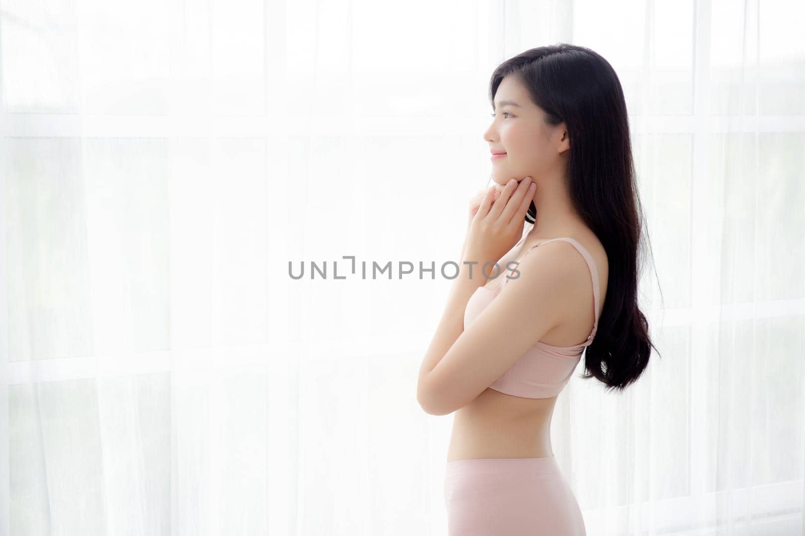 Beautiful portrait young asian woman sexy standing the window and smile while wake up with health, body of girl happy with freshness and cheerful with wellbeing, lifestyle and relax concept.