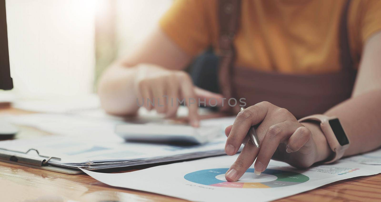 close up woman hand holding pen and pointing at financial paperwork with financial network diagram..