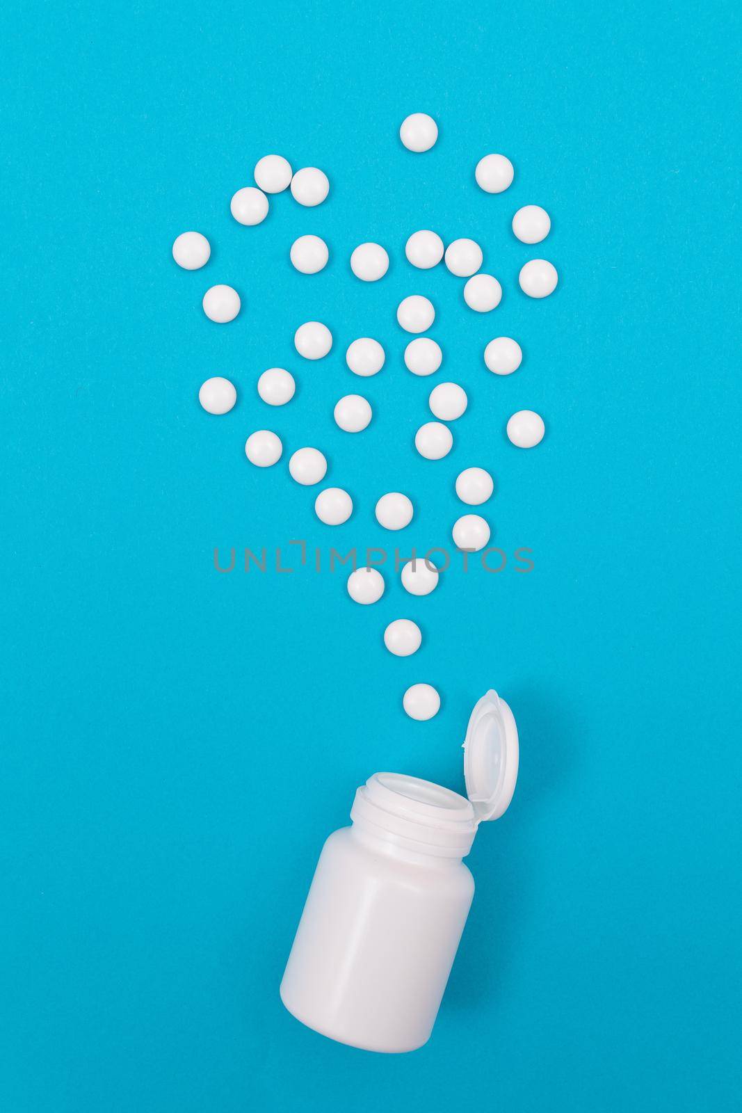 Global Pharmaceutical Industry and Medicinal Products - White Pills or Tablets Scattered from the Bottle, Lying on Blue Background, Top View, Flat Lay
