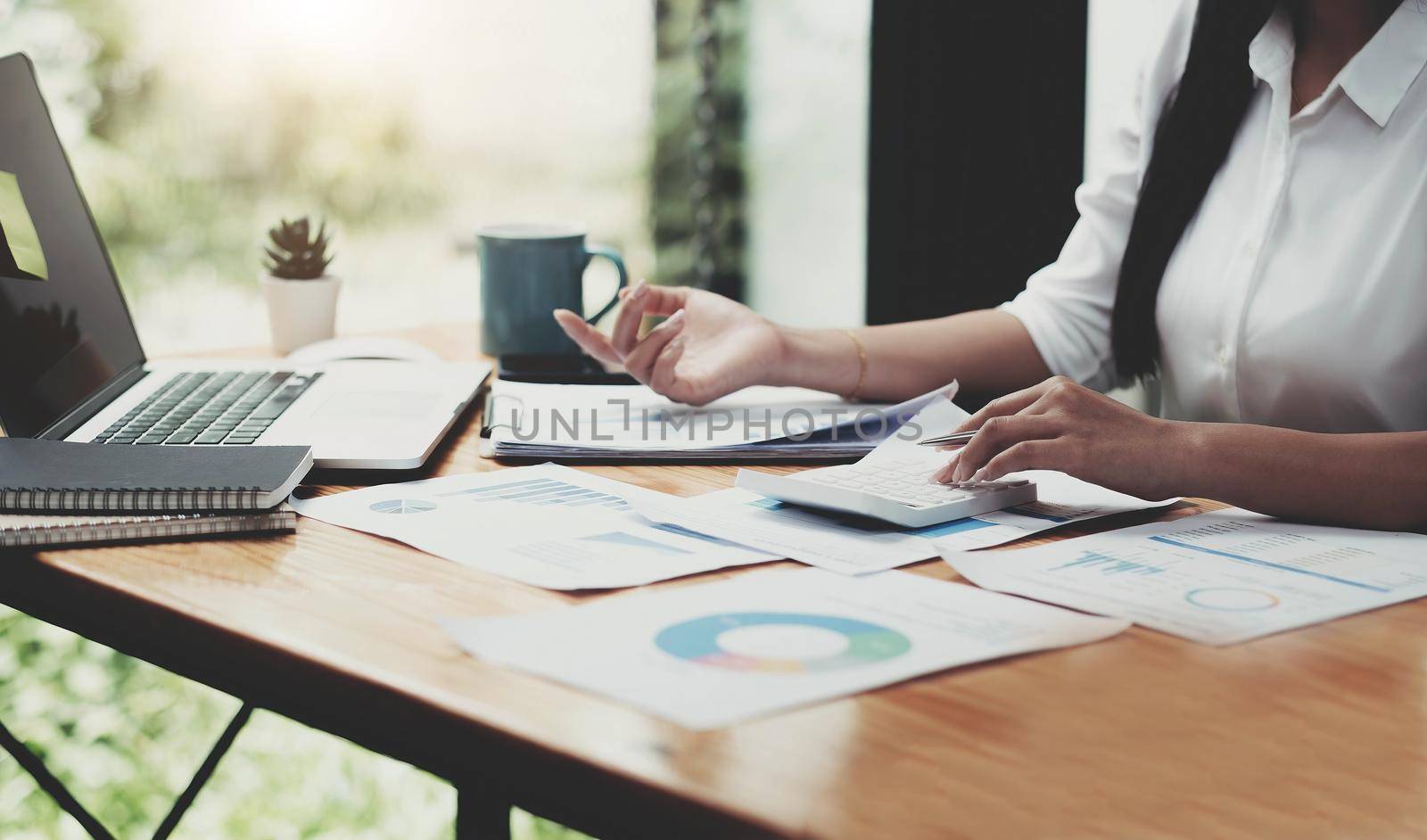 Woman hand is using the calculater to calculate the finance document by wichayada