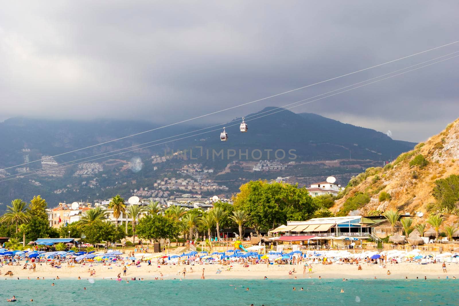 Turkey, Alanya, Cleopatra beach - August 30, 2017: People on the beach, view from the sea, against the background of mountains and funicular.