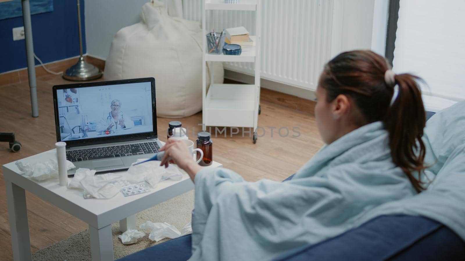 Sick patient talking to doctor on video call for telehealth with laptop. Woman showing thermometer with temperature measurement to medic on online conference, asking for treatment against fever