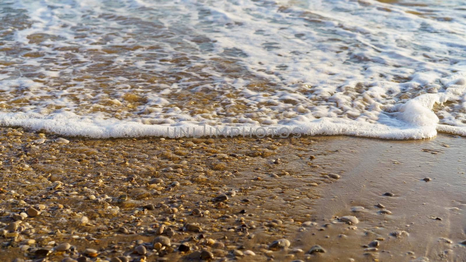 Natural background with a sea wave on a sandy beach.
