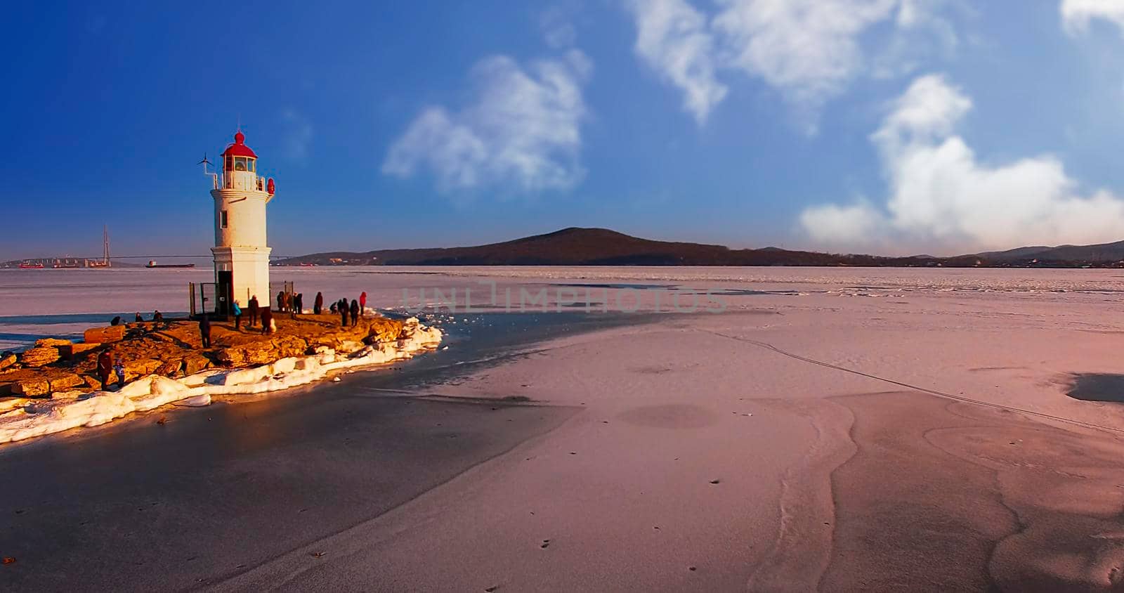 Winter landscape with a white lighthouse on the background of a frozen sea. Vladivostok, Russia