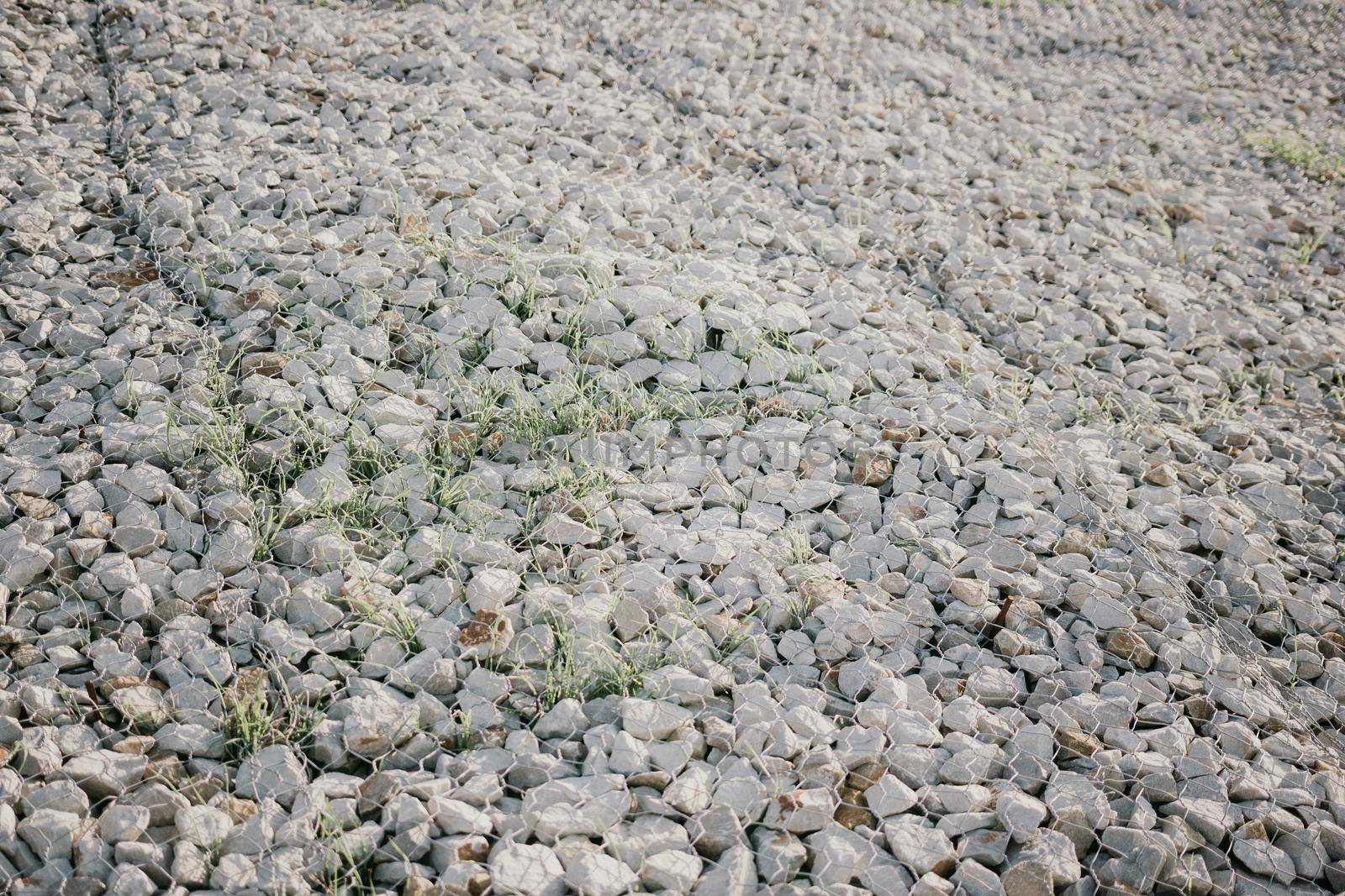 strengthening the slope with stones behind the wire. grey texture. construction. Granite stones behind a metal grate
