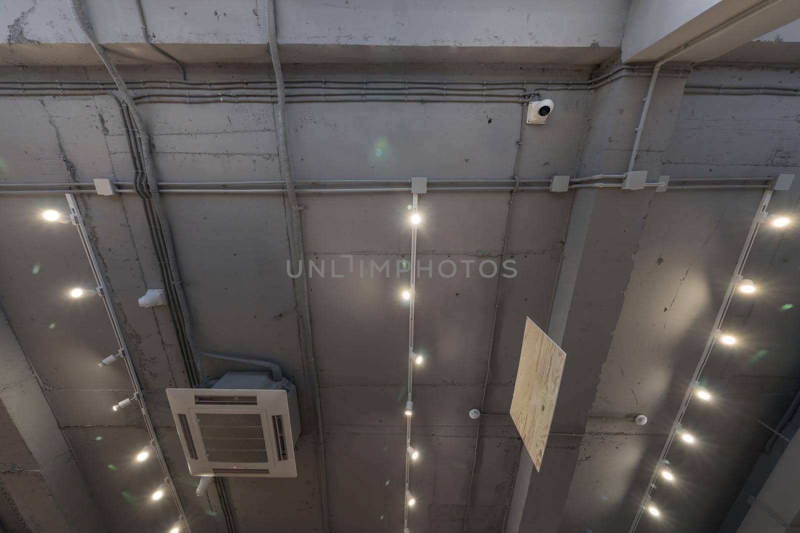 Abstract loft interior of concrete grey ceiling with air ventilation and security camera. Interior architecture and ceiling design of industrial loft building decorated with modern lamps by panophotograph