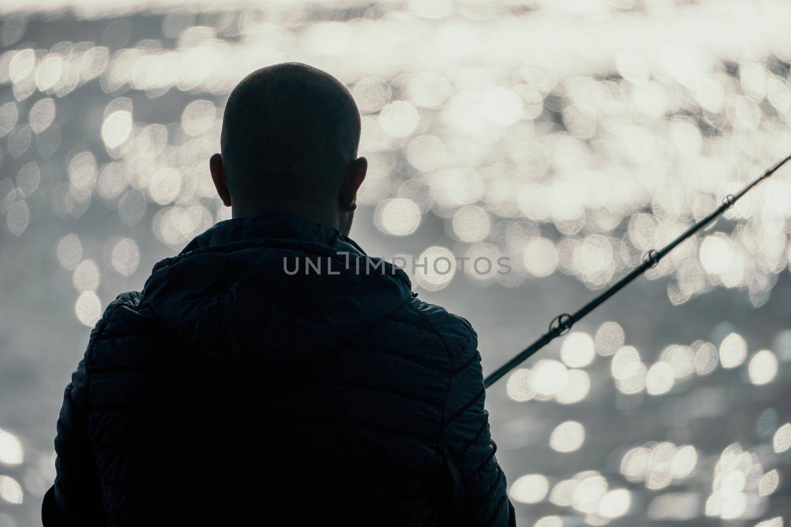 Man hobby fishing on sea tightens a fishing line reel of fish summer. Calm surface sea. Close-up of a fisherman hands twist reel with fishing line on a rod. Fishing in the blue sea outdoors