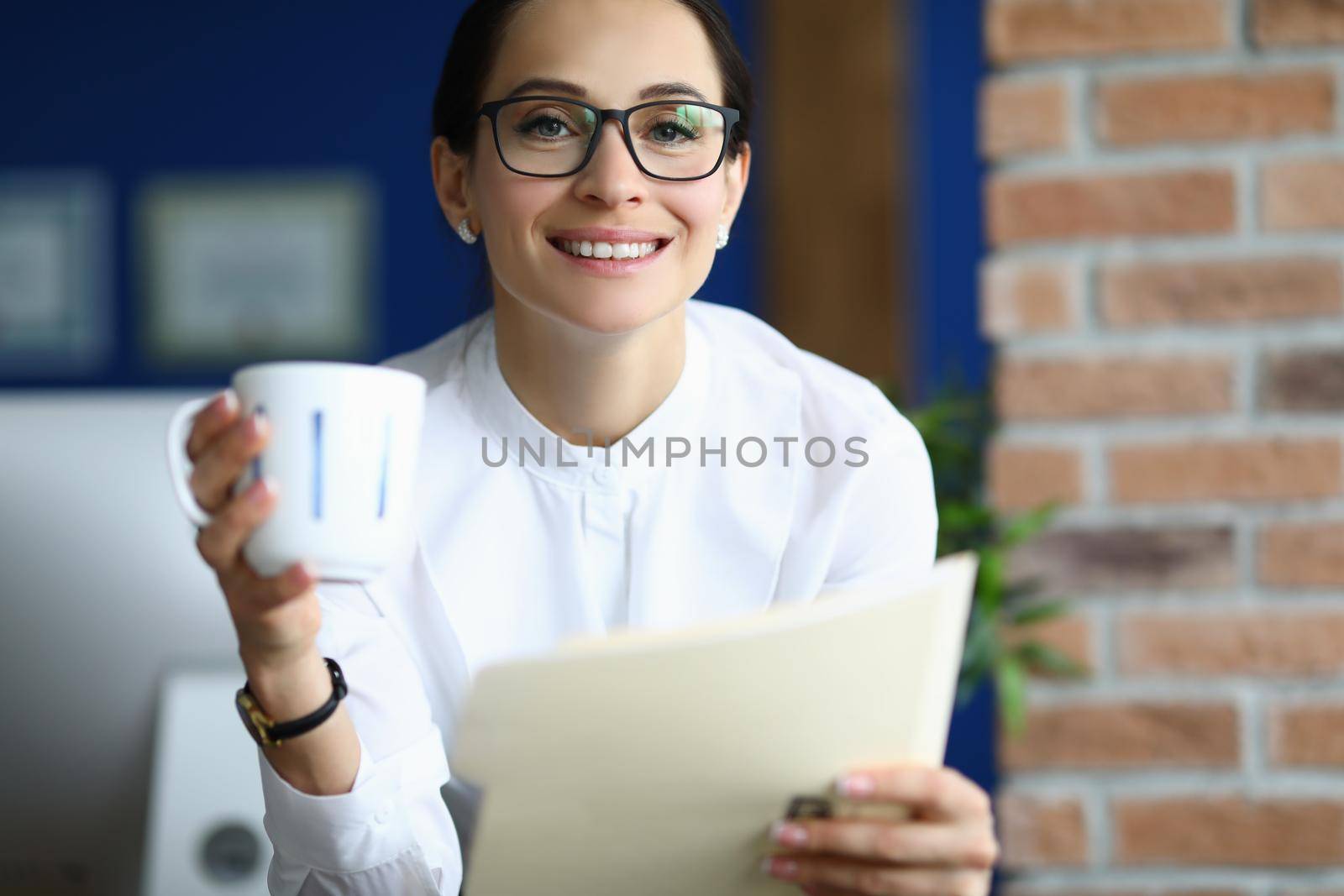 Attractive brunette businesswoman at work with cup of coffee read report by kuprevich