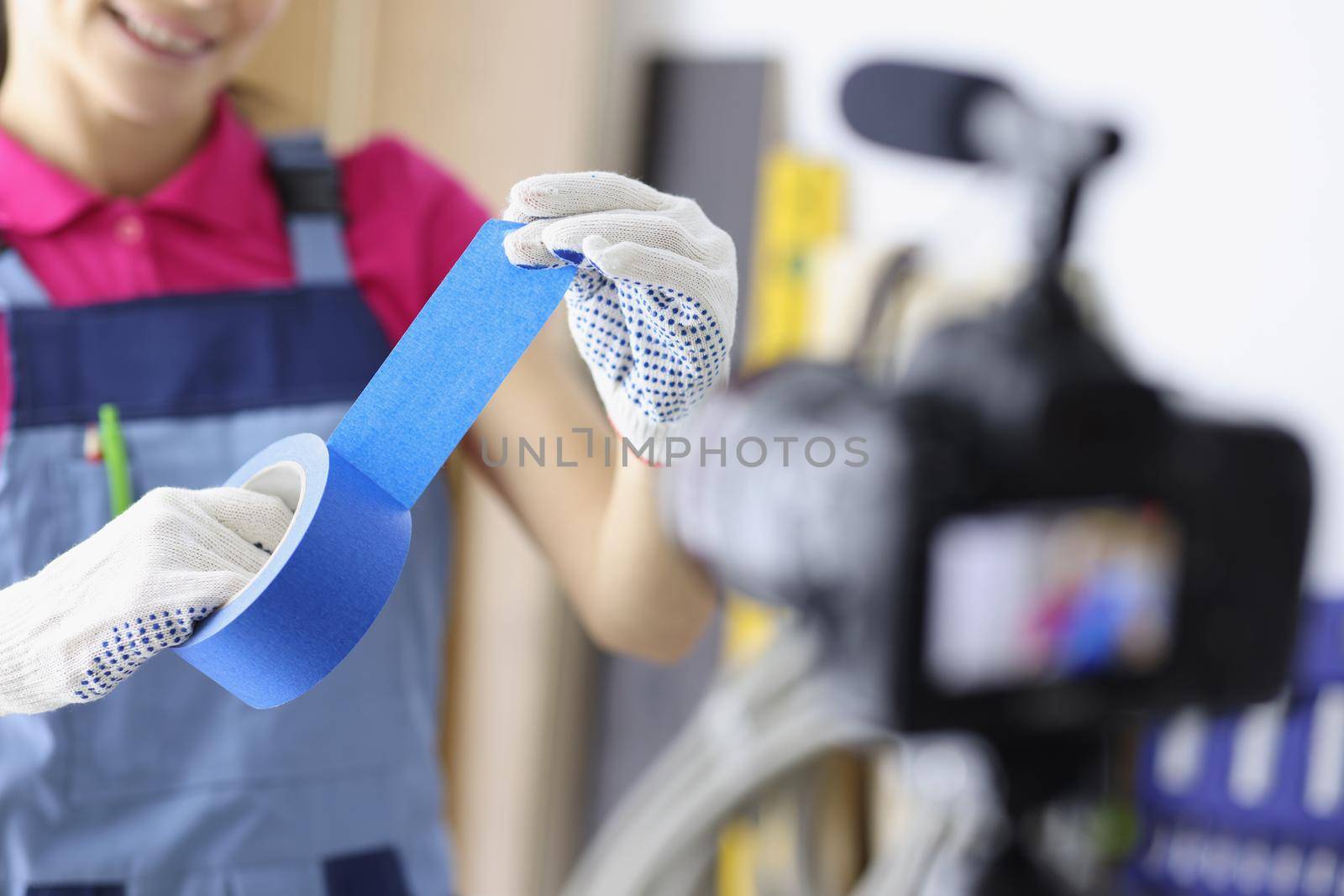 Female worker hold blue scotch and show renovation process on camera by kuprevich