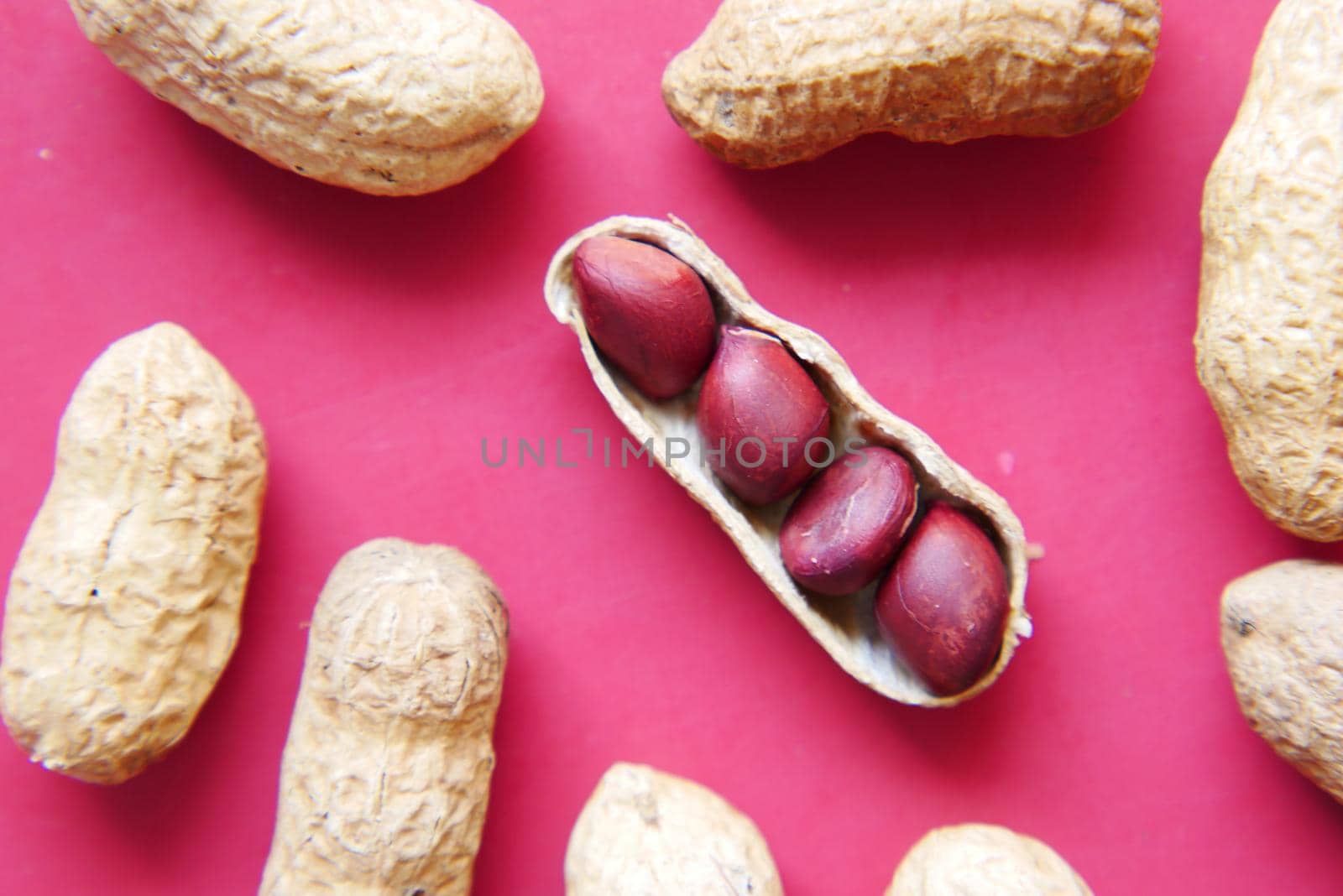 Processed pea nuts on red background close up .