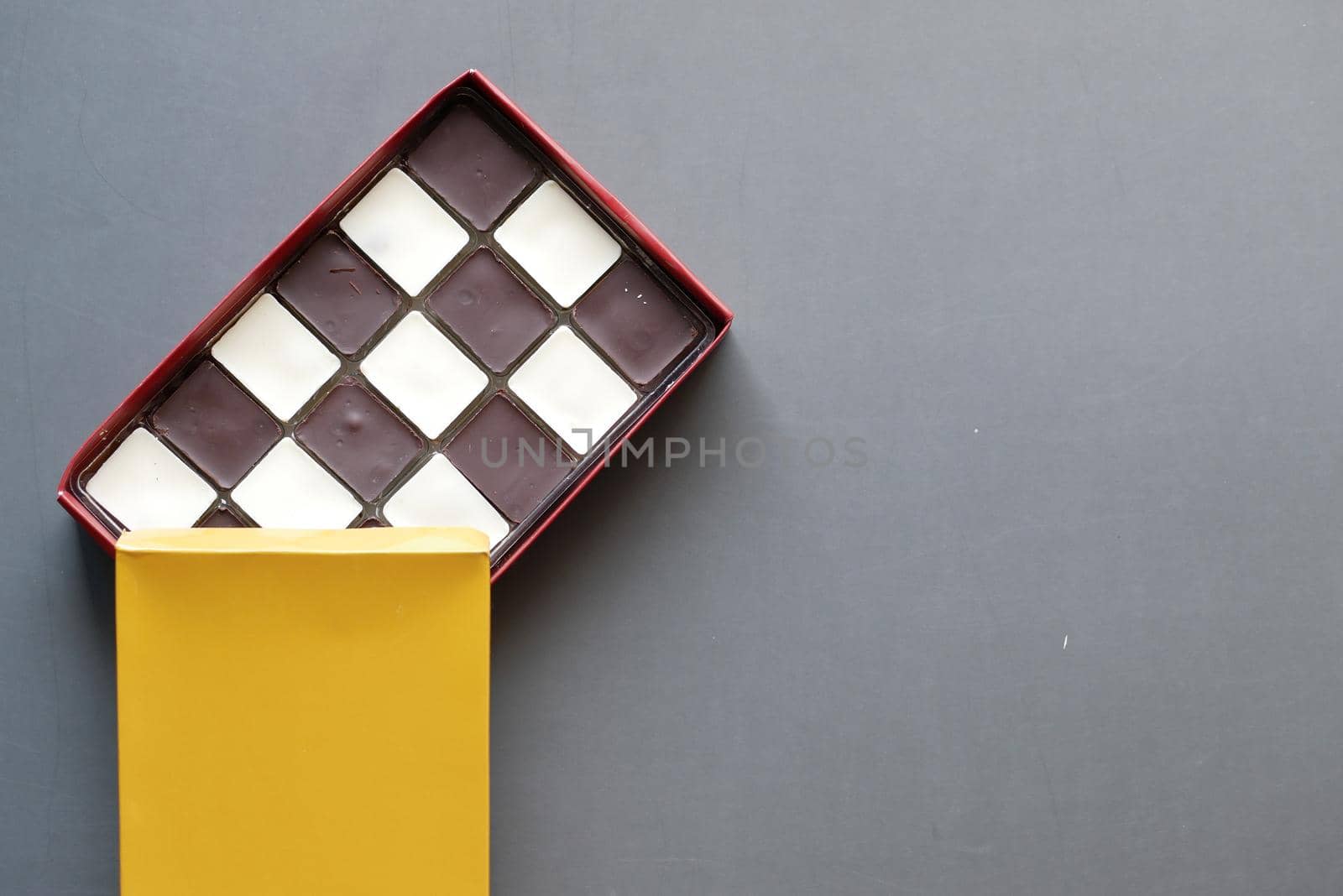 dark and white chocolate in a box on gray background .