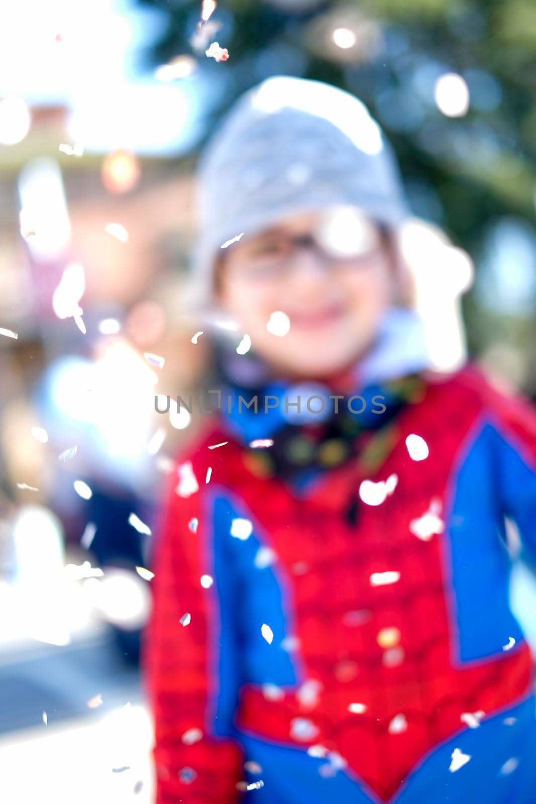 beautiful child with red spider superhero costume playing with confetti. High quality photo