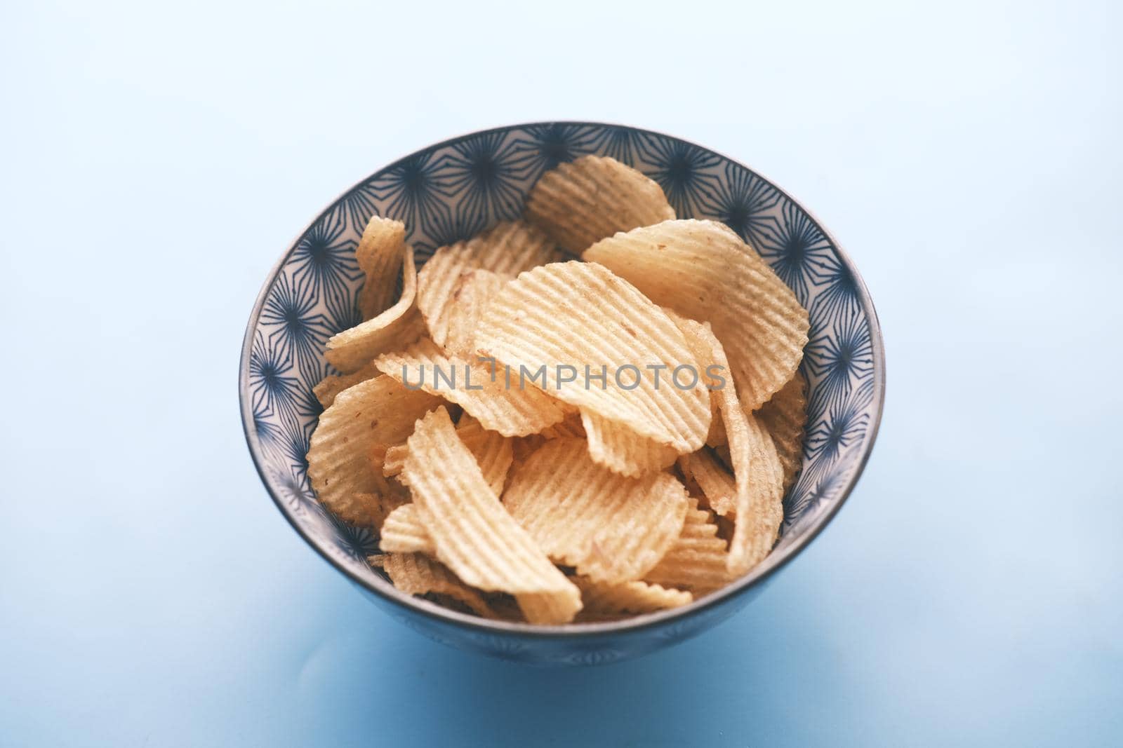 Bowl with tasty potato chips on wooden background
