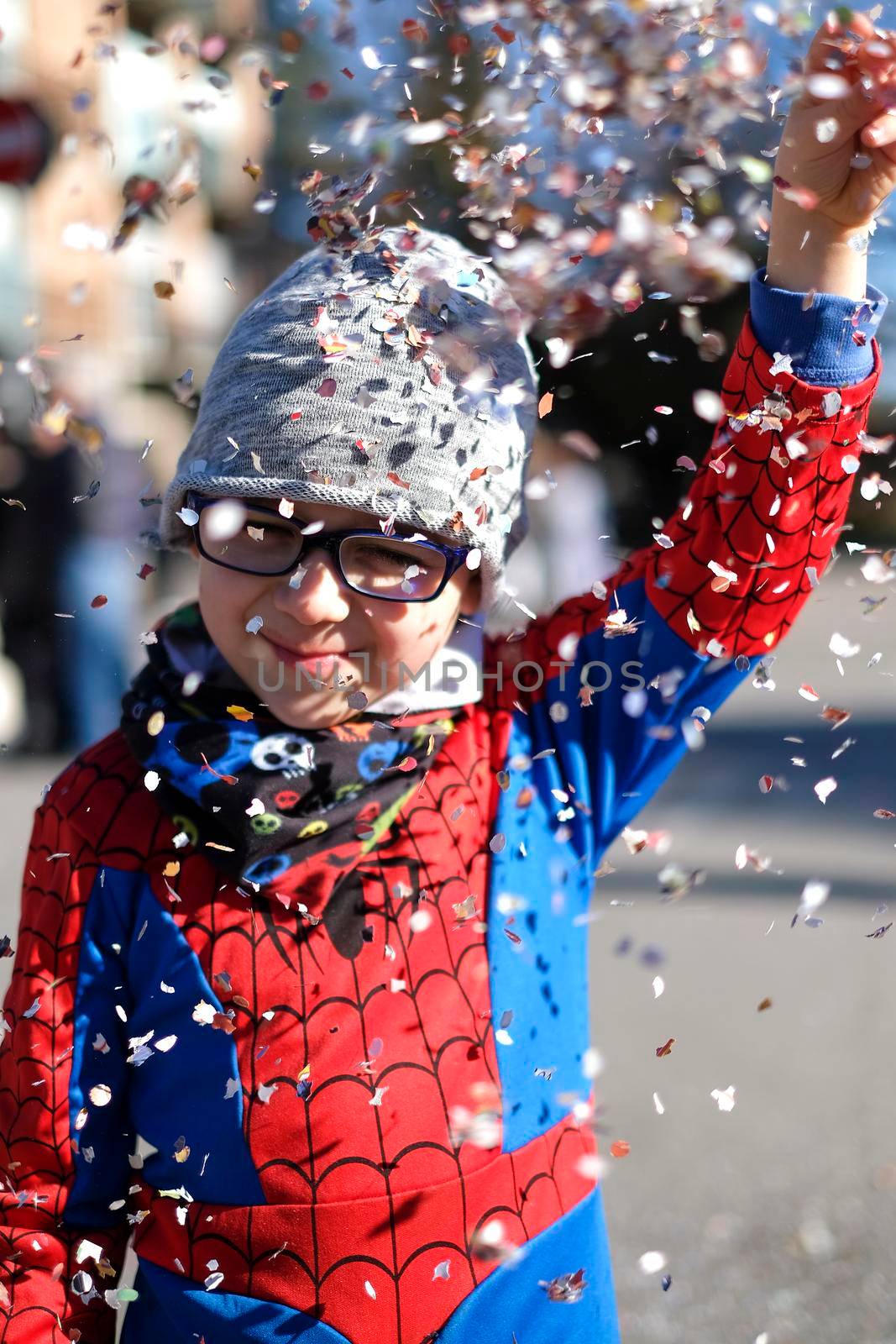 beautiful child with red spider superhero costume playing with confetti. High quality photo