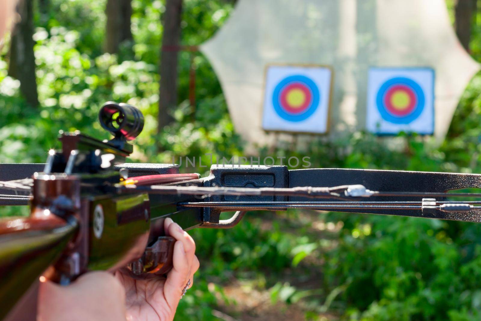 Woman aiming crossbow at target outdoor