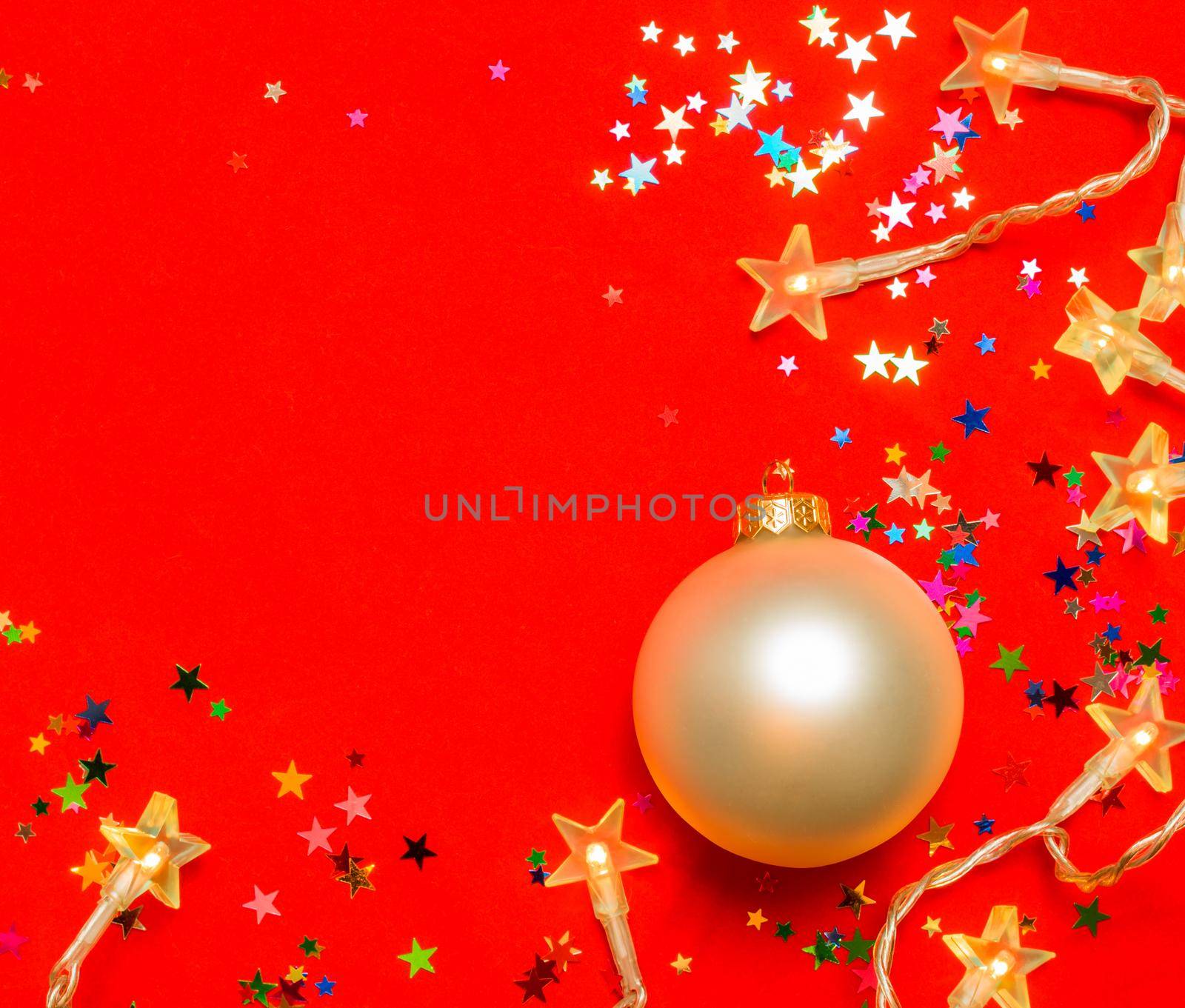 Christmas bauble with star-shaped lights and confetti on red background