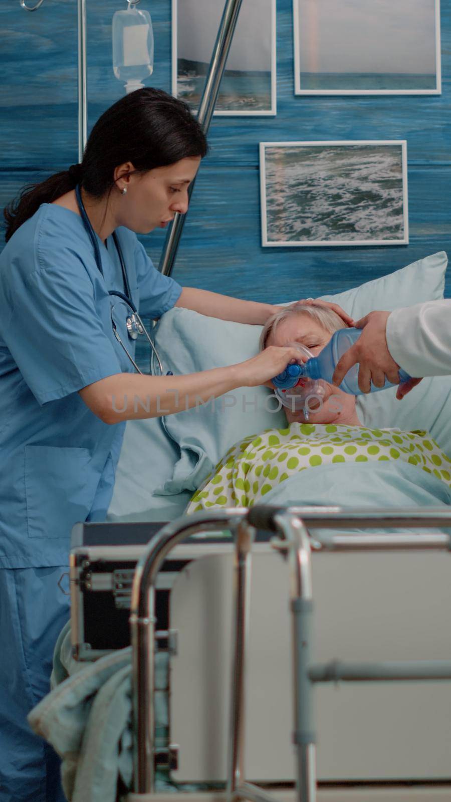 Doctor and nurse helping elder patient with disease in bed. Medical team rushing to help retired woman with resuscitation for recovery and healthcare. Specialists giving assistance