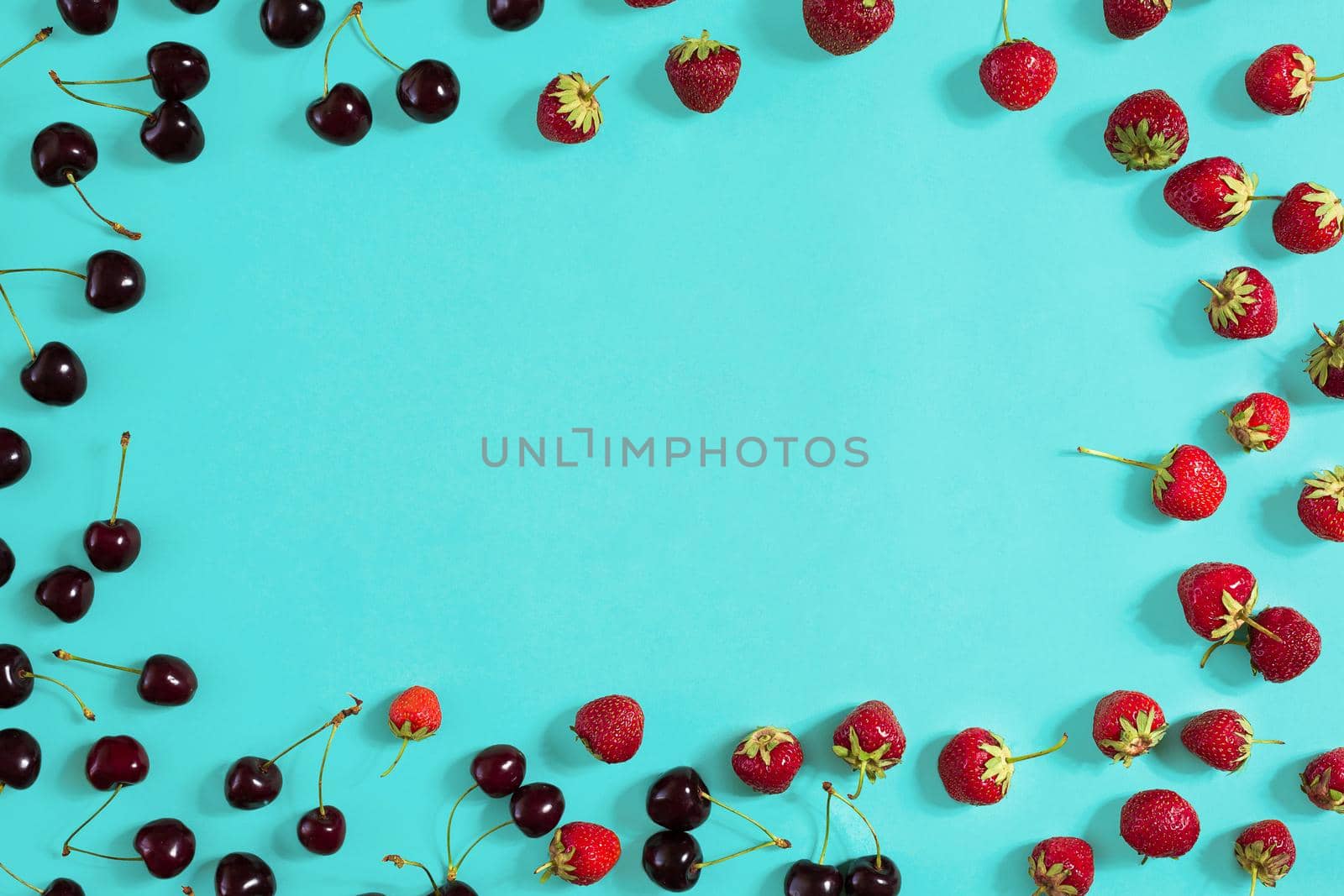 Strawberry and cherries on a blue background. Top view. Copy space. Still life. Flat lay.