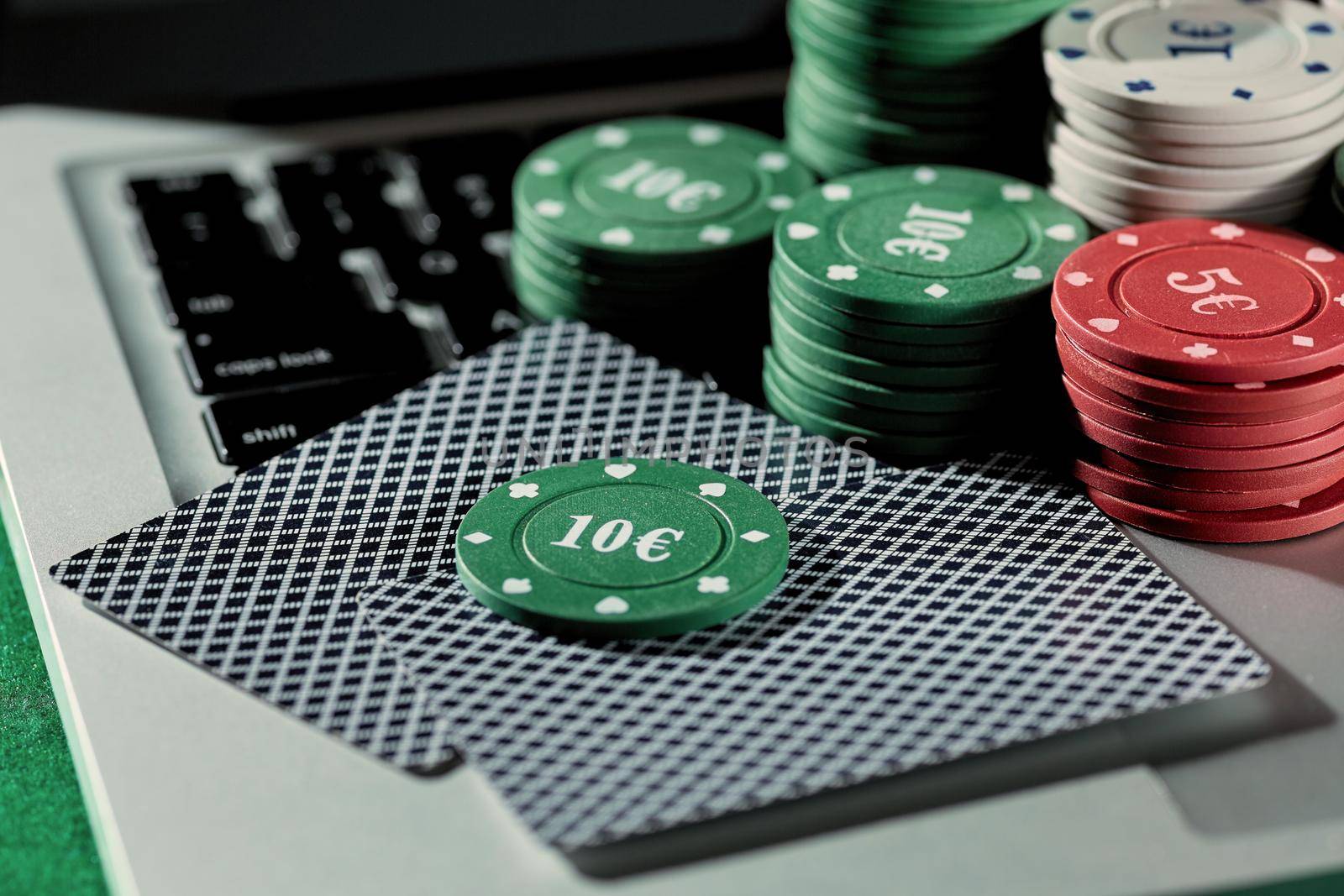 View of casino chips and cards on a laptop to play online. Concept for online gambling, poker, virtual casino.