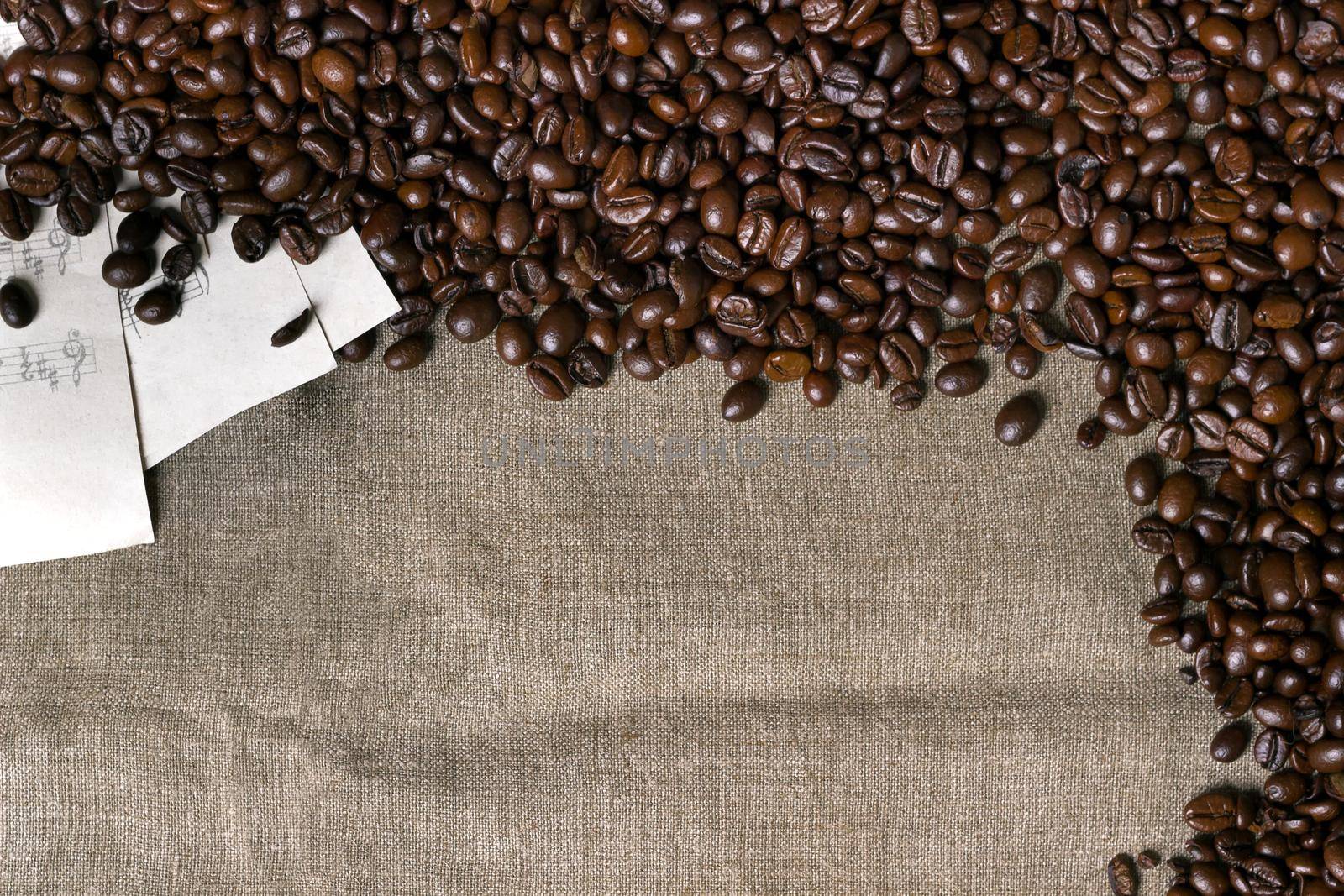 Coffee beans and sheet music on burlap background. Top view. Copy space. Still life. Mock-up. Flat lay