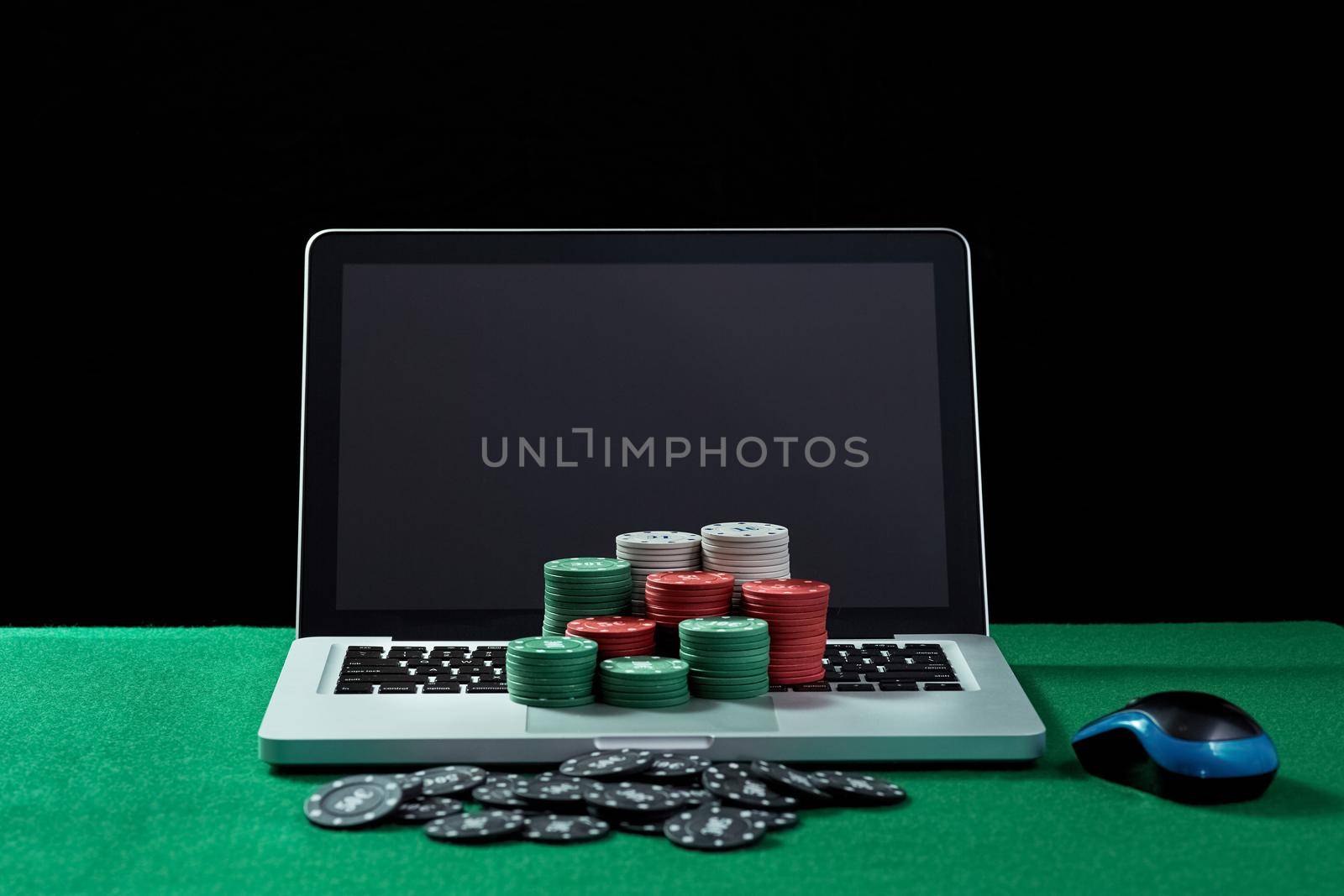 Image of casino chips on a keyboard notebook at green table. Concept for online gambling, poker, virtual casino.