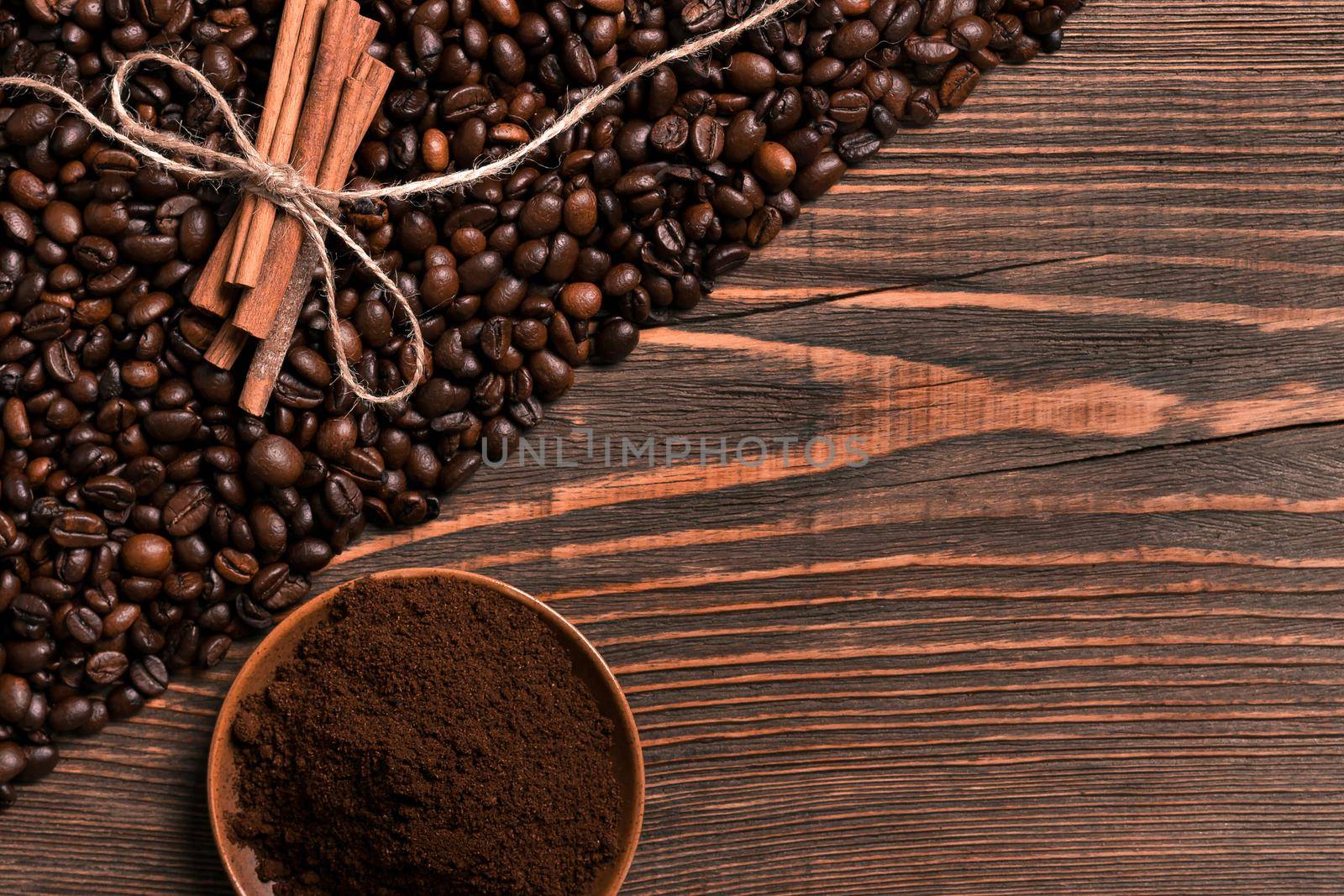 Coffee beans, cinnamon sticks and ground coffee on rustic wooden table, view from above with space for text. Still life. Mock-up. Flat lay