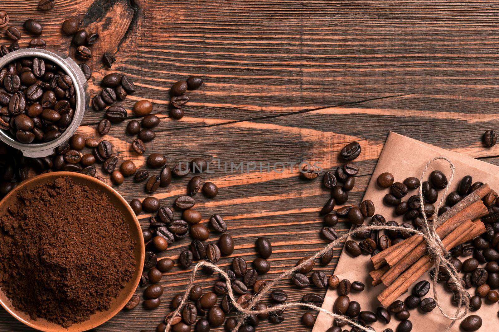 Coffee beans, cinnamon sticks and ground coffee on rustic wooden table, view from above with space for text. Still life. Mock-up. Flat lay