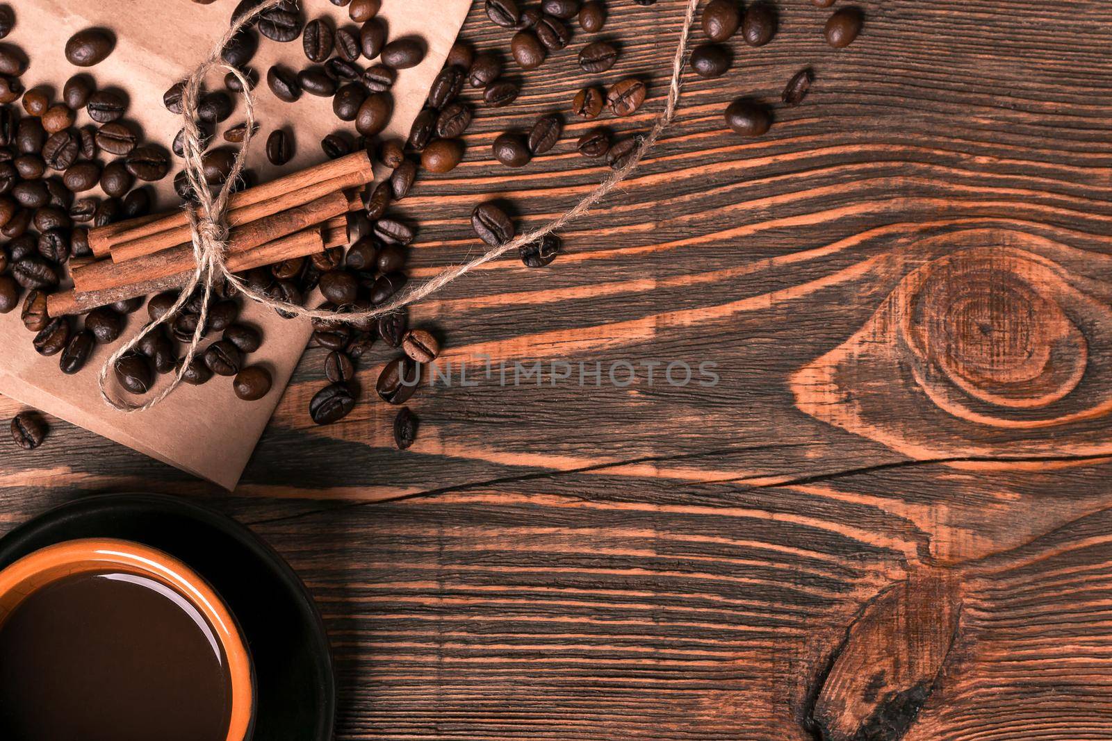 Coffe cup, coffee beans on wooden table background with cinnamon. Top view. Still life. Copy space. Flat lay.