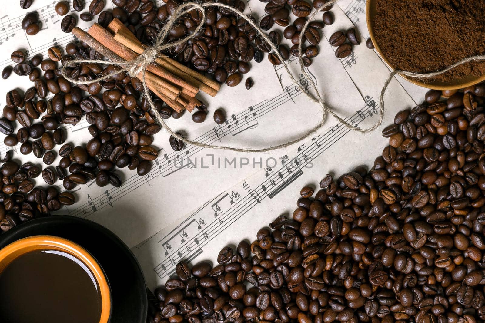 Coffee beans, ground coffee and cup of brewed coffee on sheet music background, view from above with space for text. Still life. Mock-up. Flat lay
