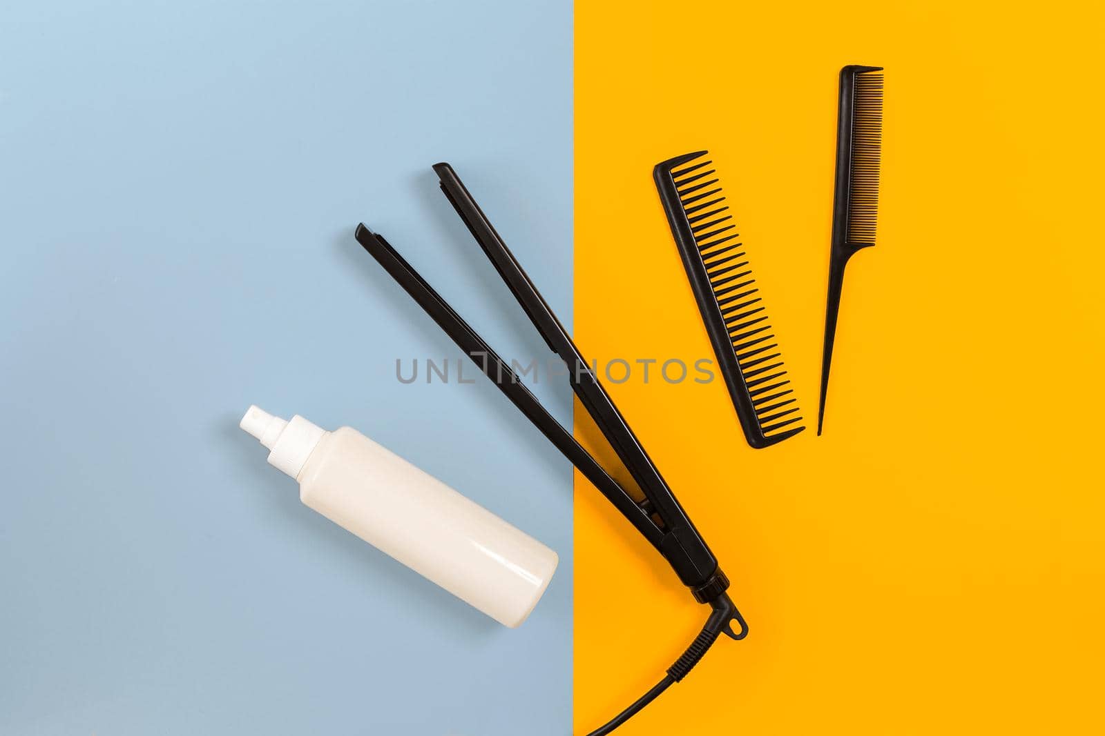 Various hair styling devices on the color blue, yellow paper background, top view by nazarovsergey