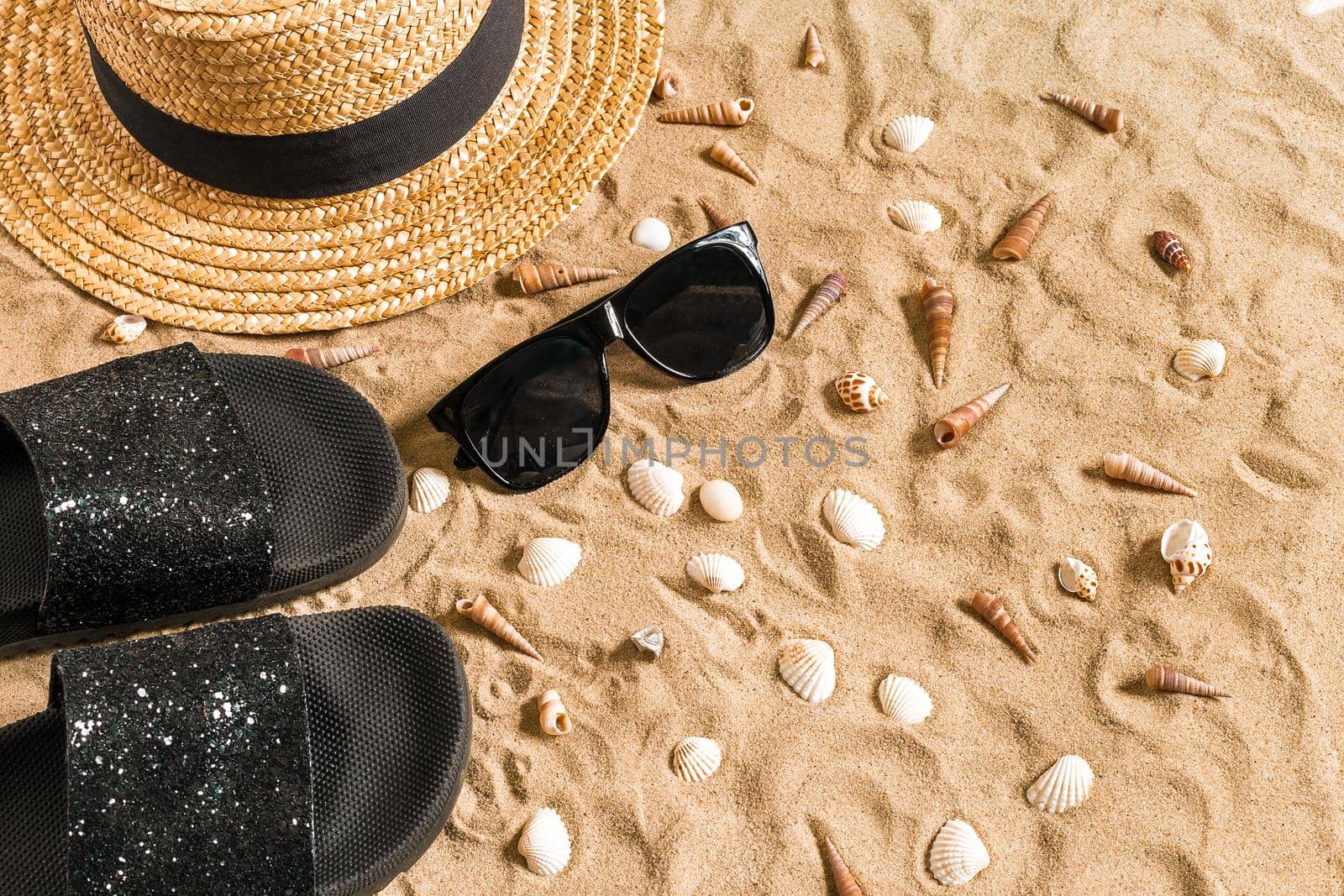 Summer beachwear, flip flops, hat, sunglasses and seashells on sand beach. Top view. Copy space. Still life mockup flat lay